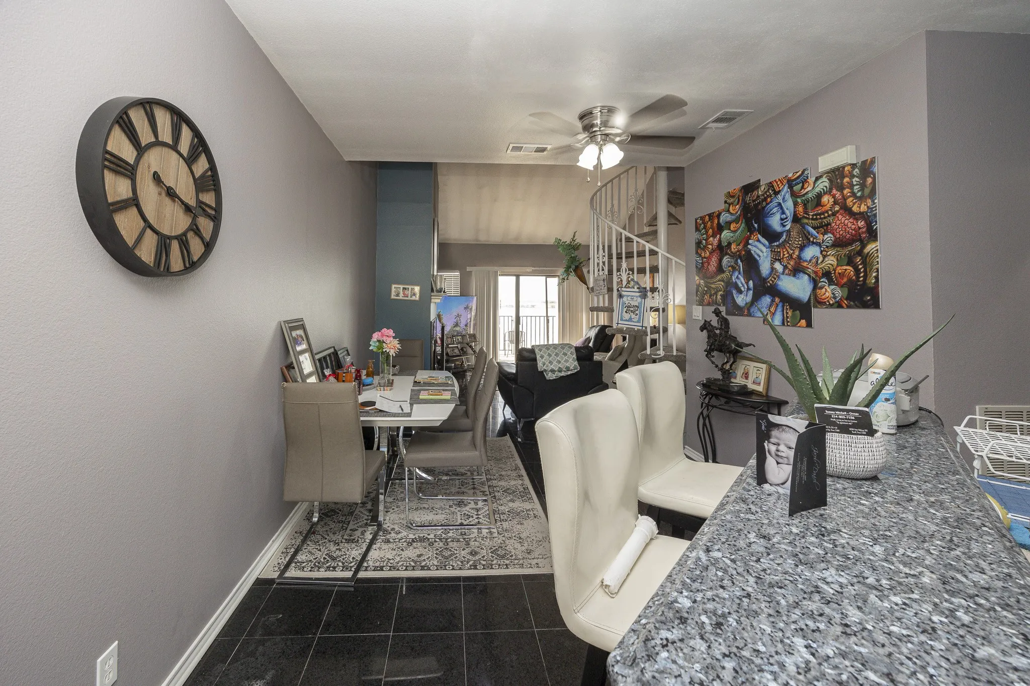 Black tile flooring with a speckled countertop, a white spiral staircase, and ceiling fan