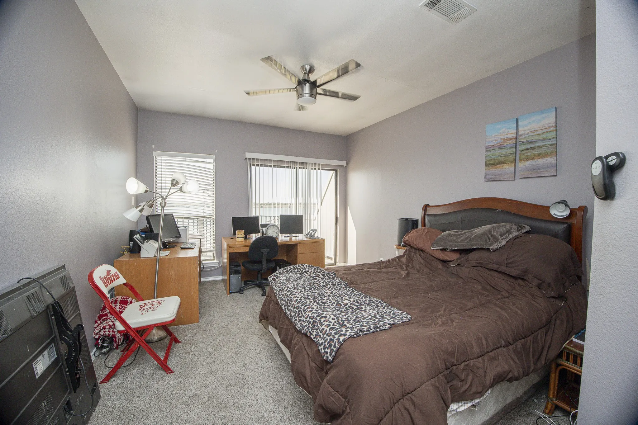 Carpeted room with a ceiling fan, a window with blinds, and a sliding glass door