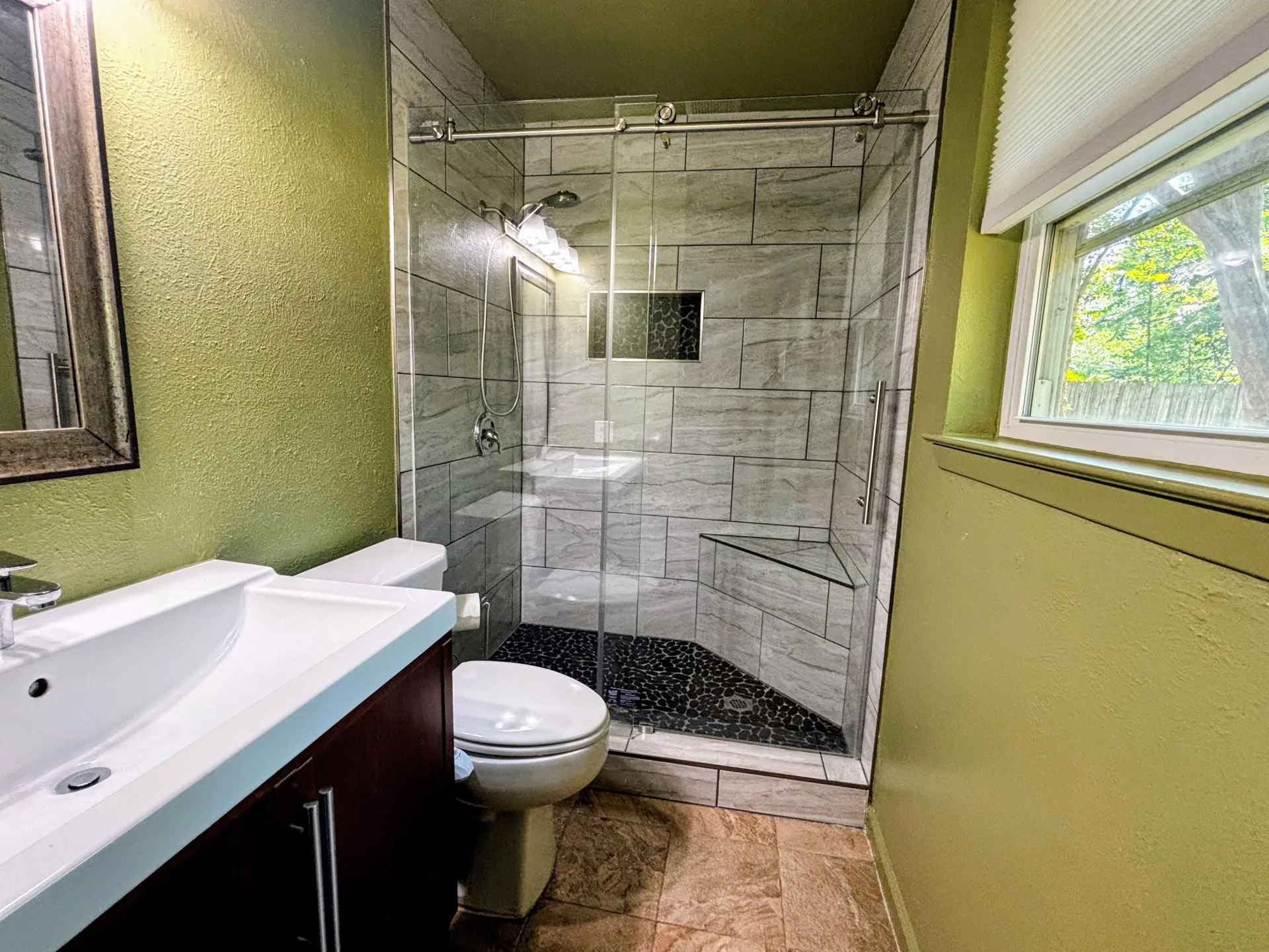 Glass-enclosed shower with subway tile surround, integrated shower niche, and corner bench