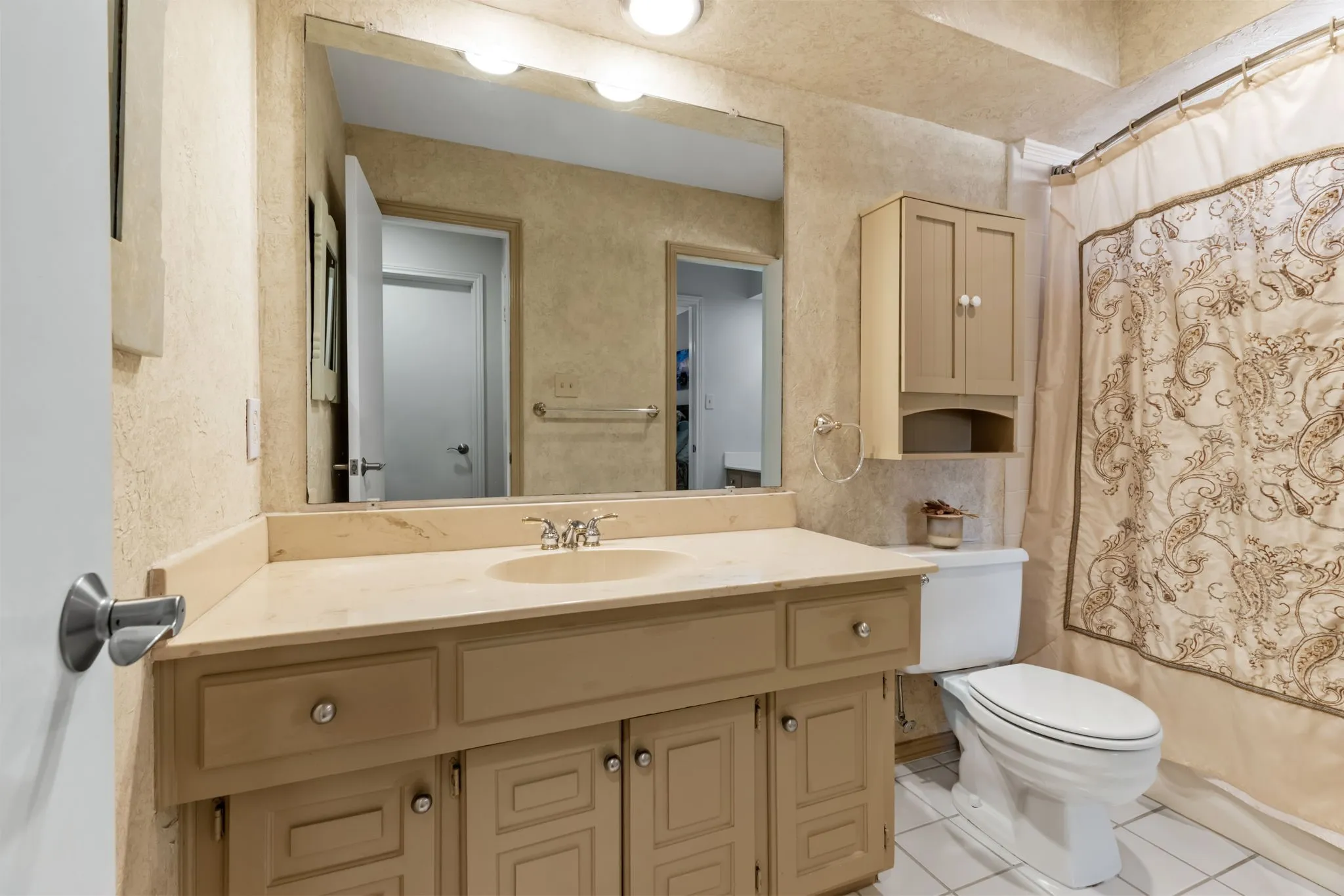 Vanity with an integrated sink and light-toned countertop, accompanied by a wall-mounted medicine cabinet, and a toilet