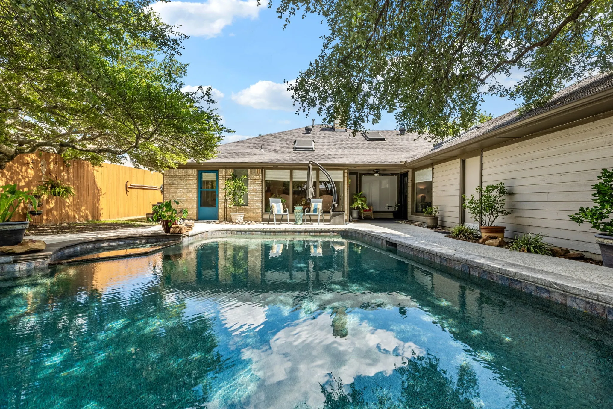 Swimming pool with integrated spa, stone coping, and surrounding concrete decking