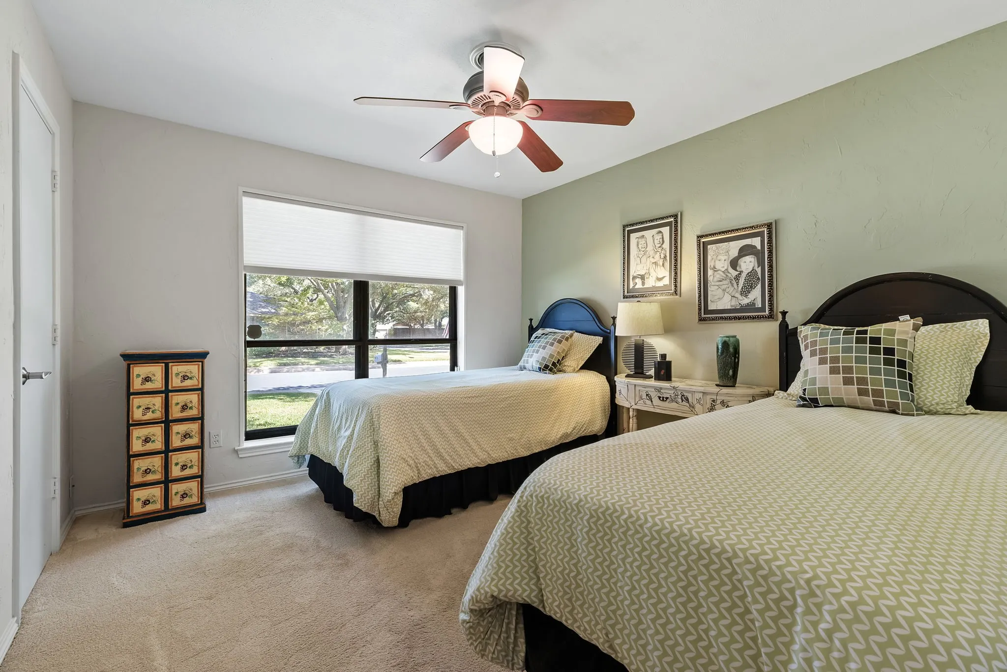 Carpeted room with a ceiling fan, window with blinds, and a light green accent wall