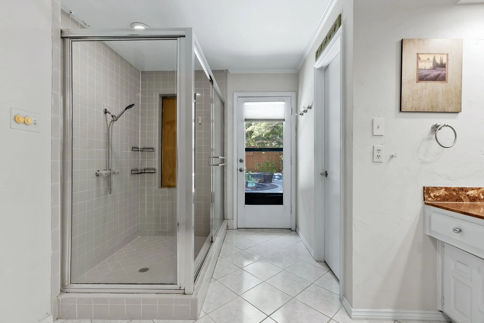 Glass-enclosed shower with tile surround and built-in shelving