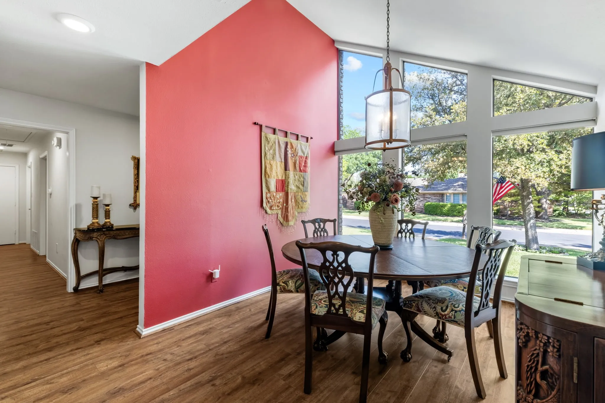 Vaulted ceilings, expansive window wall, wood-finish flooring, recessed lighting, and a decorative pendant light fixture