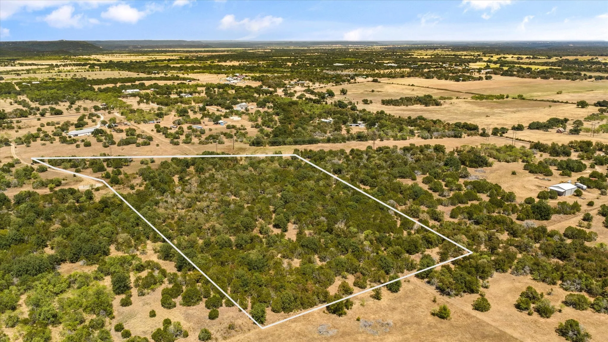 Expansive land parcel with dense tree coverage, surrounded by vast open terrain