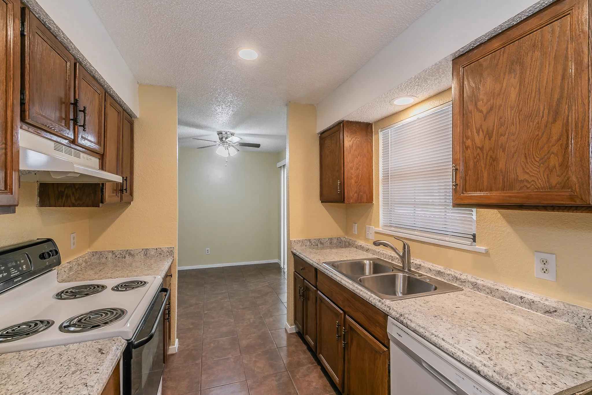 Kitchen with dark tile patterned floors, a textured ceiling, white electric range, ceiling fan, and sink