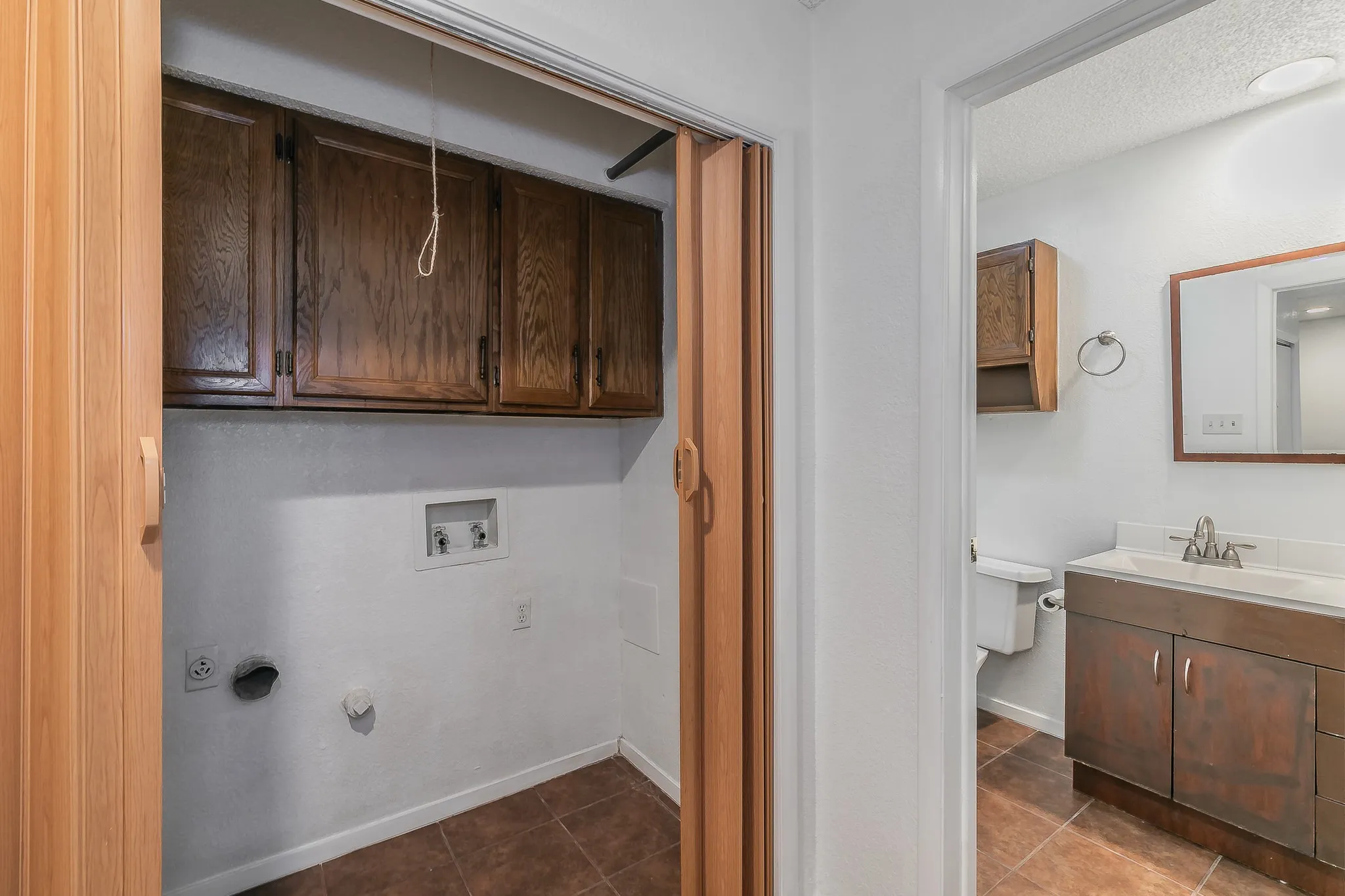 Clothes washing area with hookup for a gas dryer, sink, cabinets, tile patterned flooring, and washer hookup