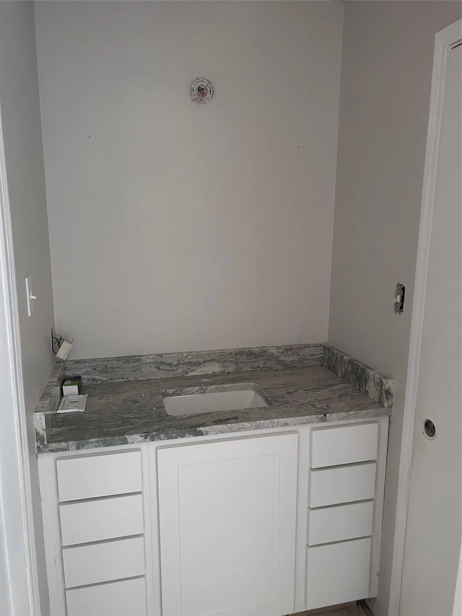Renovations underway. Private bathroom with new cabinets, granite counters, and sink. Coming soon: new mirror, light fixture, hardware, and vinyl plank flooring.