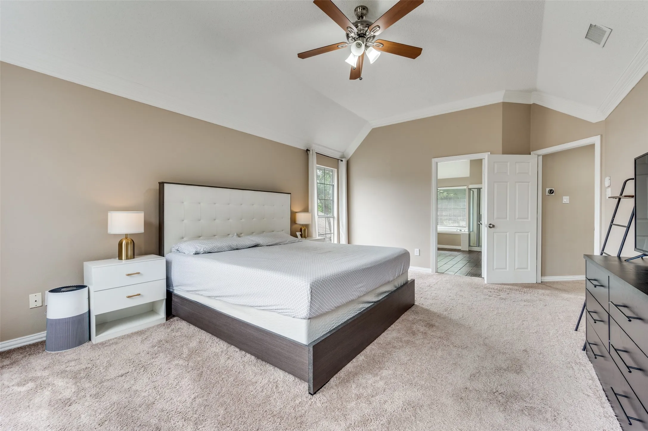 Vaulted ceiling with crown molding, ceiling fan, and light-toned carpet flooring