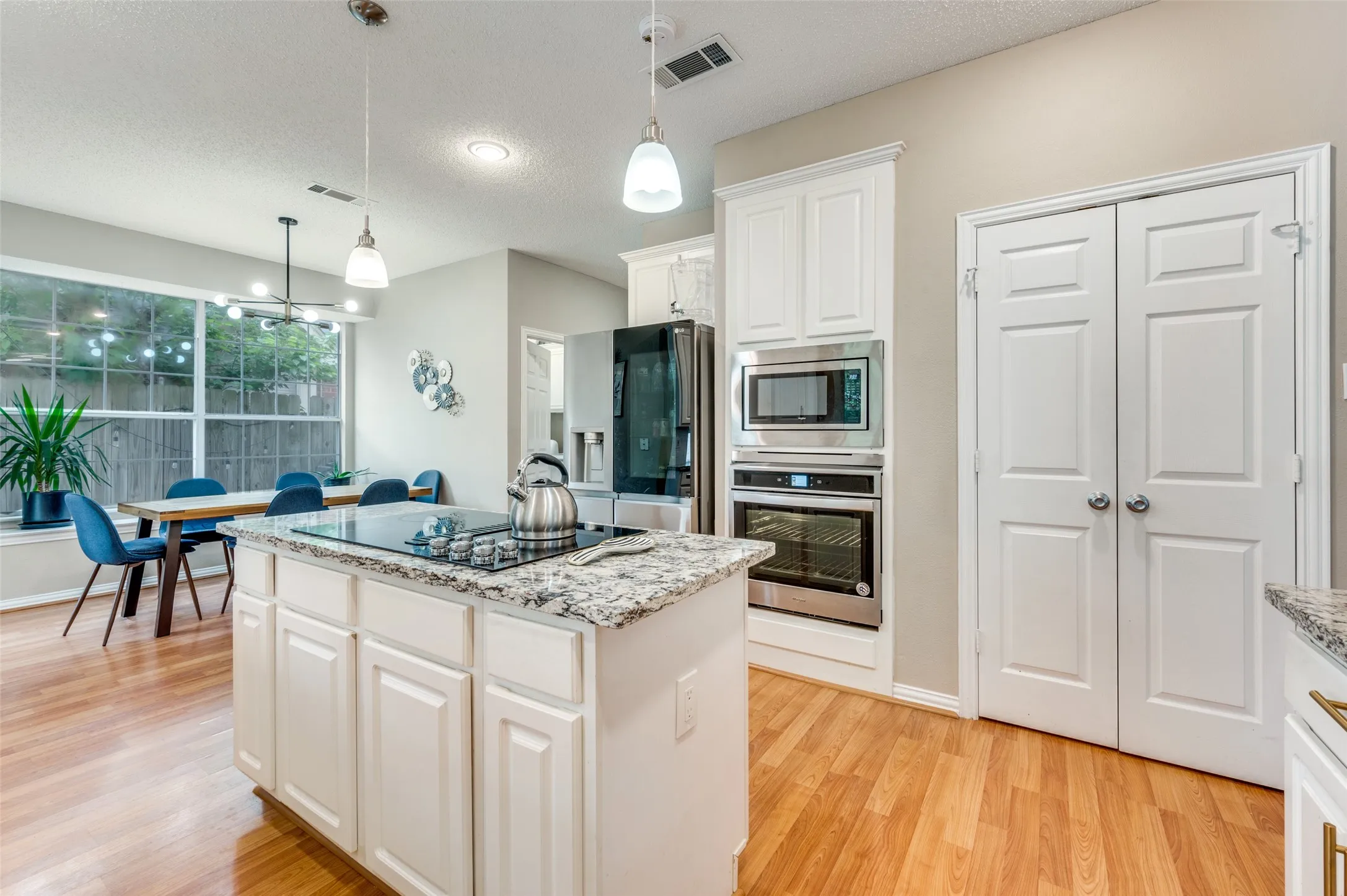 Kitchen island with granite countertop, built-in cooktop, and white cabinetry