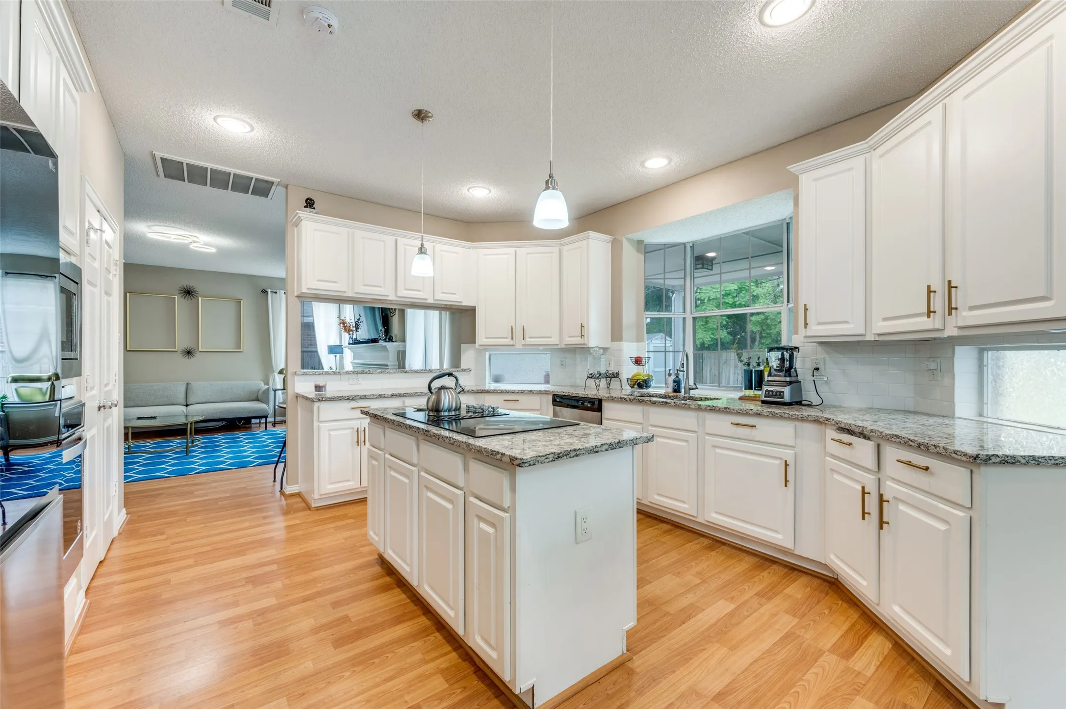 Kitchen featuring white cabinetry, stone countertops, wood-finish flooring, recessed lighting, and a kitchen island with cooktop