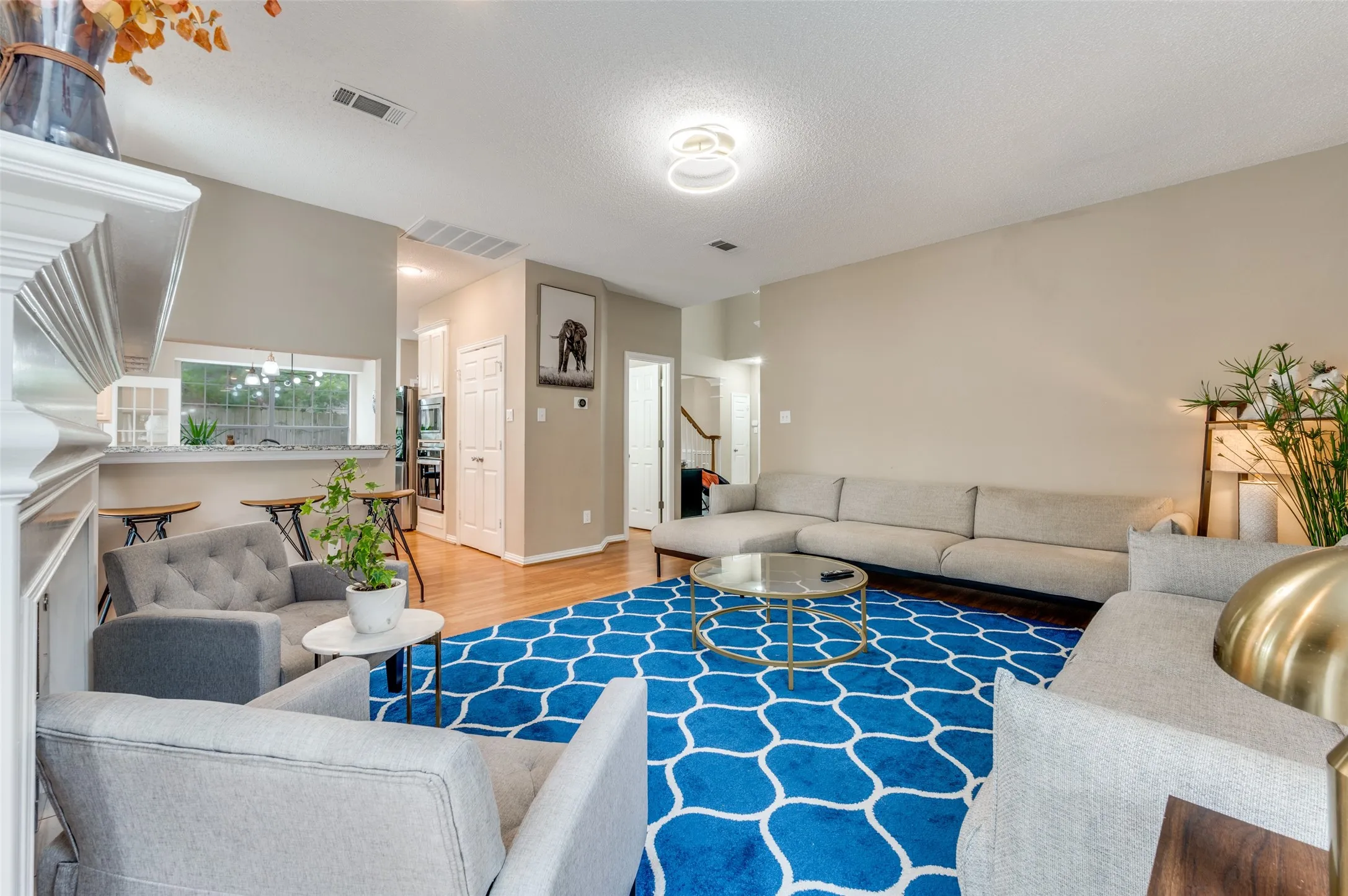 Wood-finish flooring throughout, vaulted ceiling, built-in breakfast bar, open-concept layout, and modern ceiling light fixture
