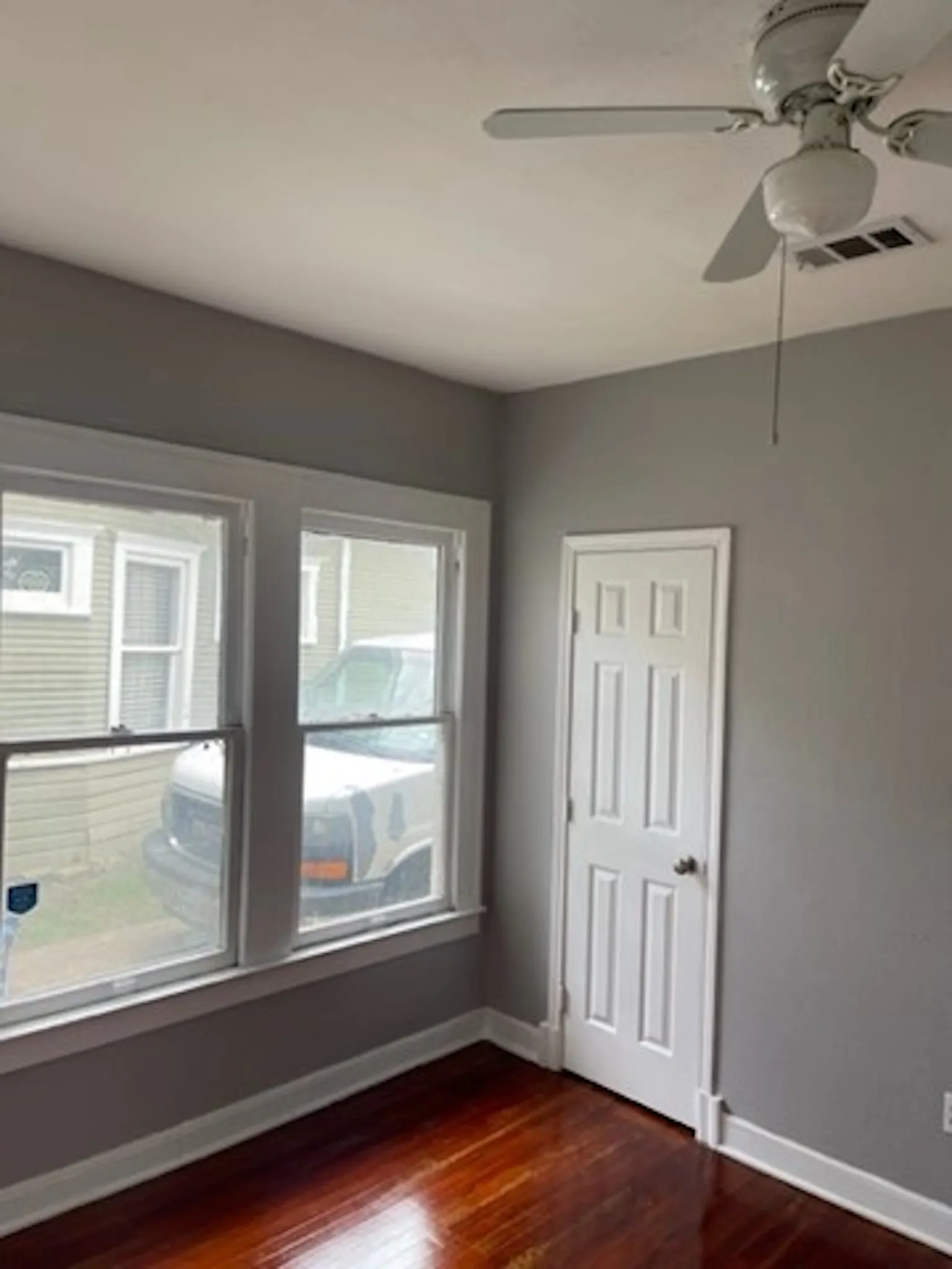 Unfurnished room with dark wood-style flooring, visible vents, and baseboards