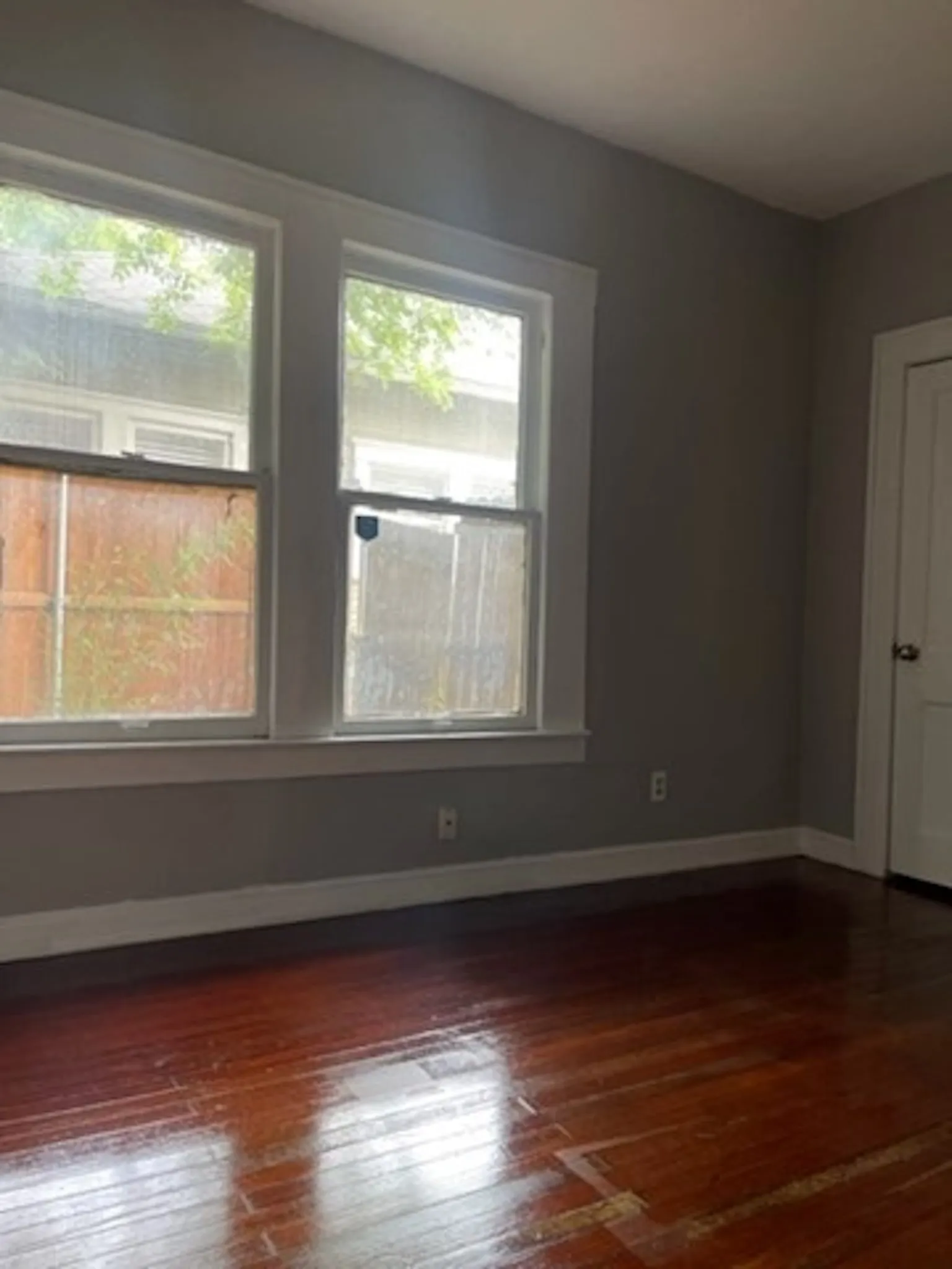Unfurnished room featuring baseboards, dark wood-type flooring, and a healthy amount of sunlight