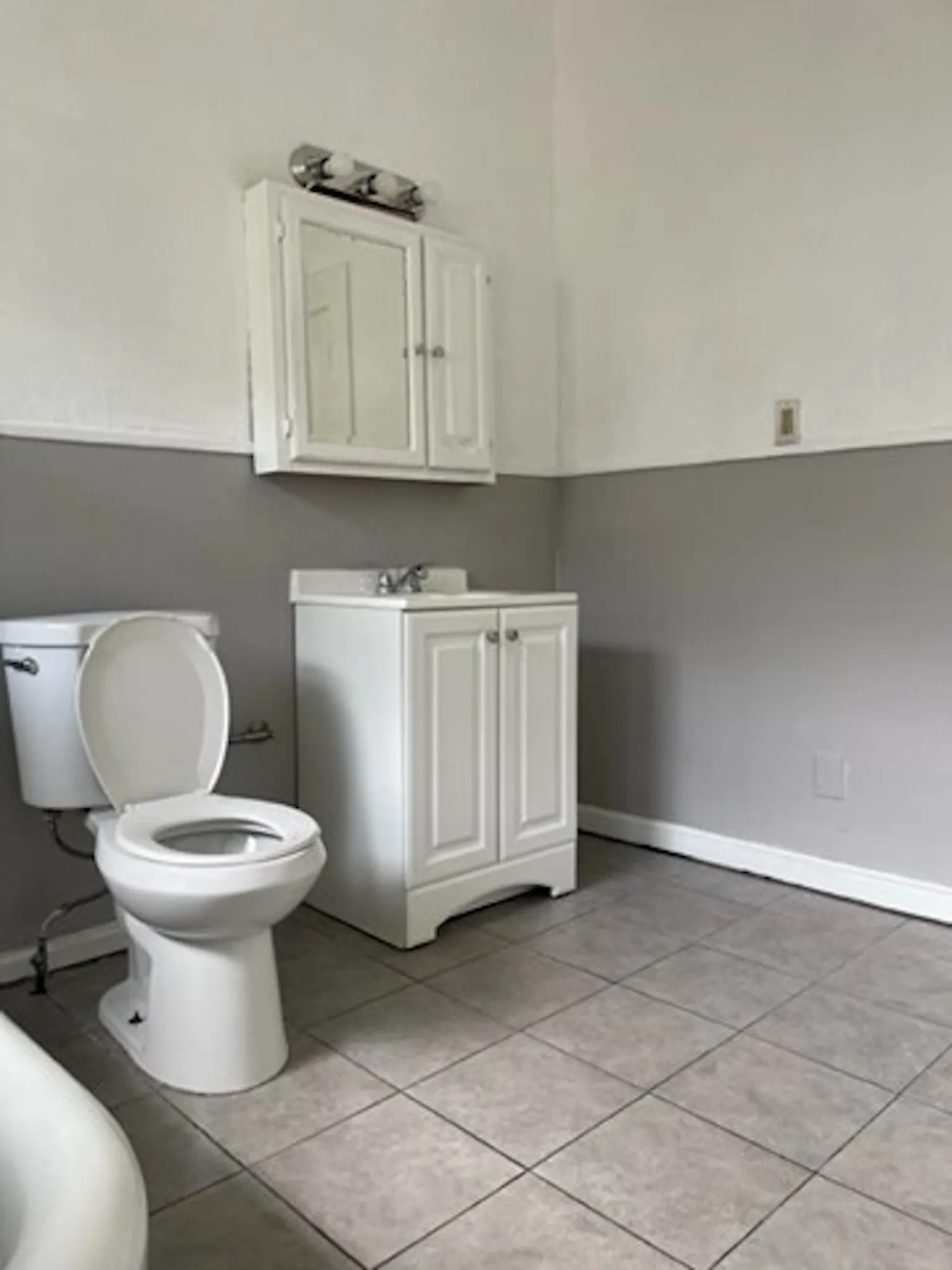 Bathroom featuring tile patterned flooring, baseboards, vanity, and toilet