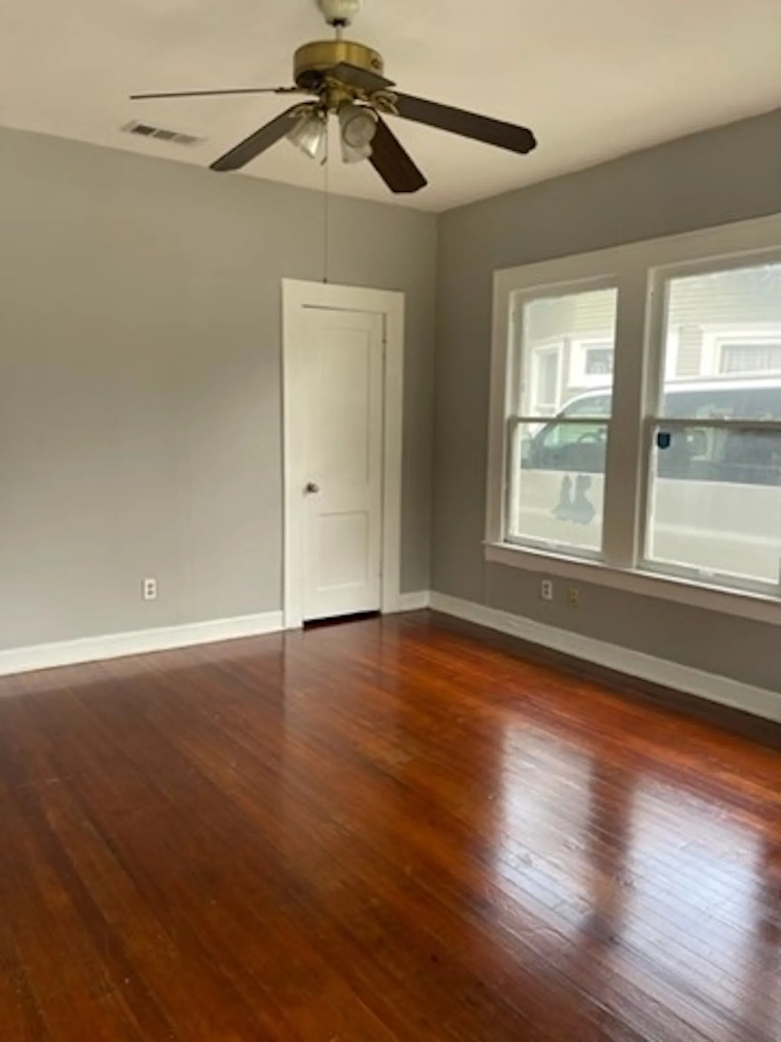 Spare room with ceiling fan, dark wood finished floors, visible vents, and baseboards