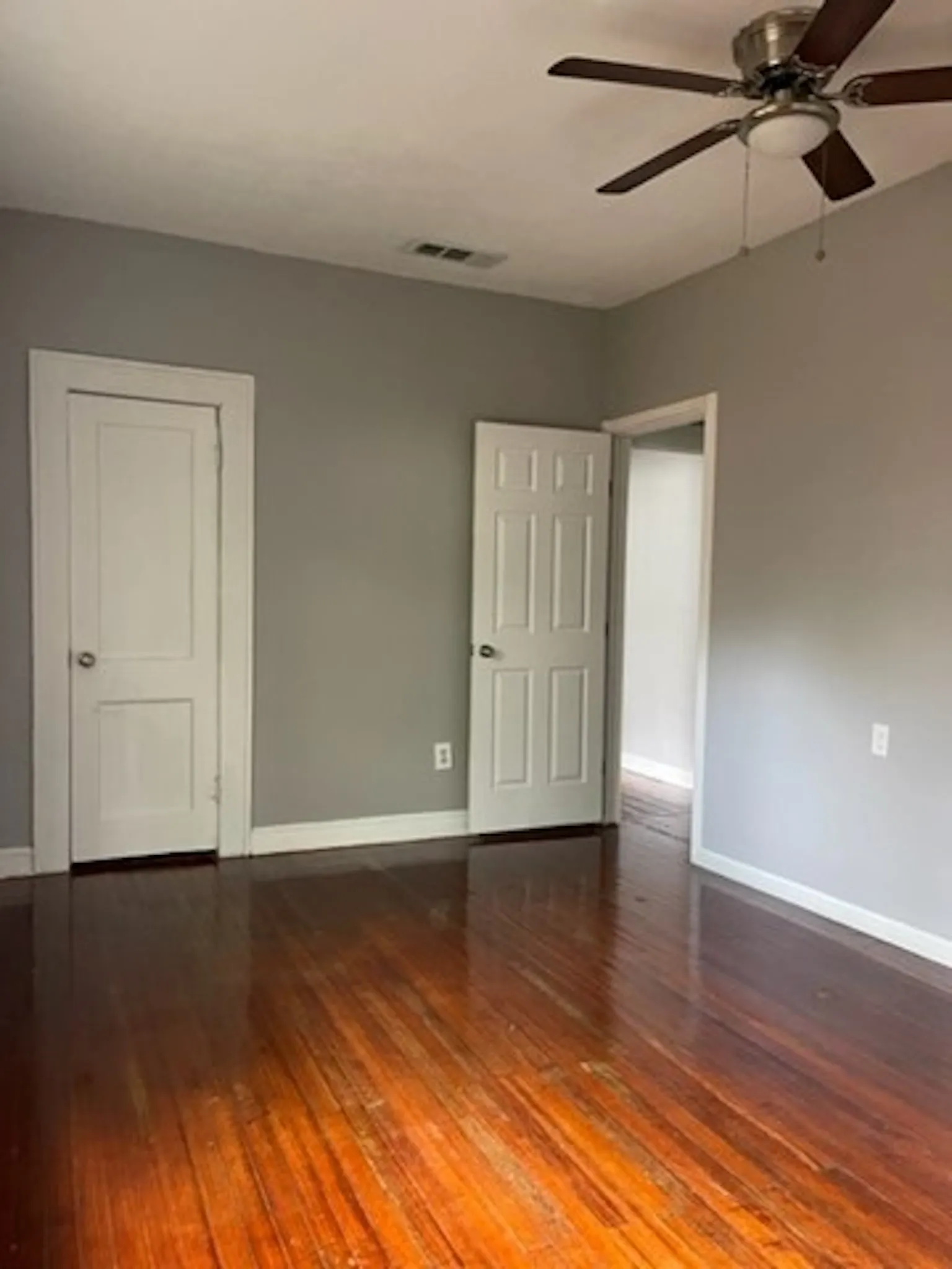 Unfurnished room featuring dark wood-type flooring, visible vents, and baseboards