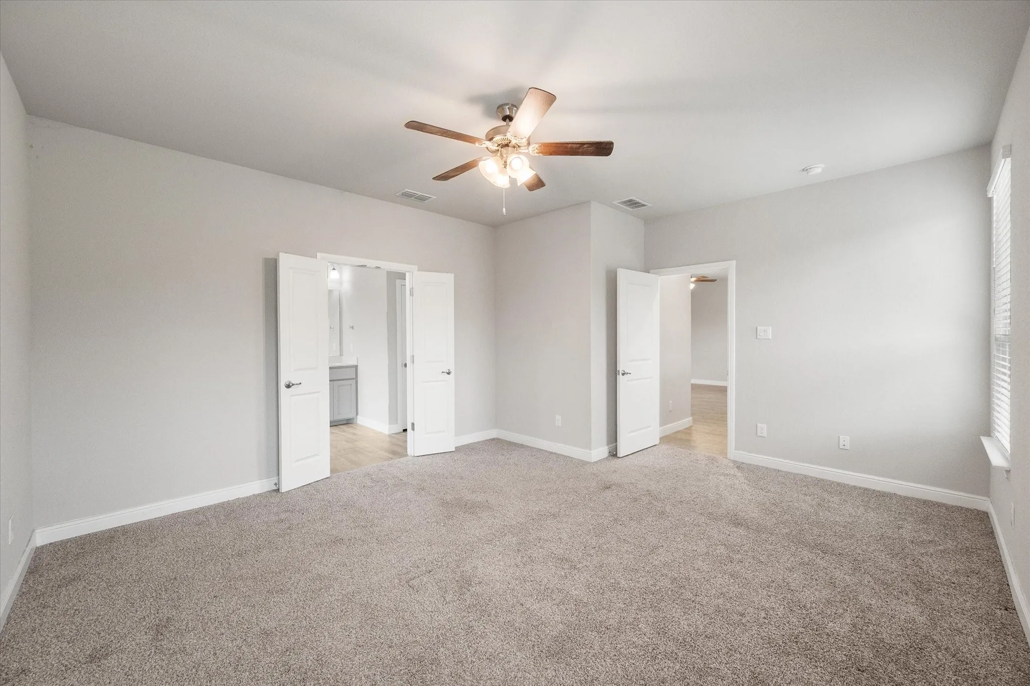 Private primary bedroom with plush carpet flooring, neutral wall paint and an en-suite bathroom