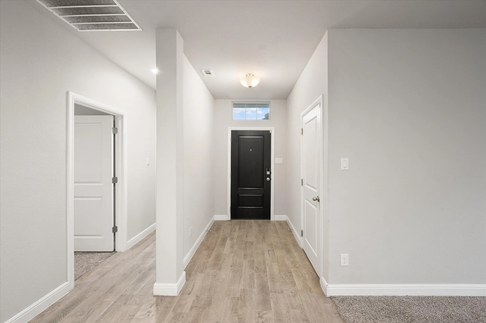 Entryway featuring wood-look tile flooring and a contemporary black door with transom window!