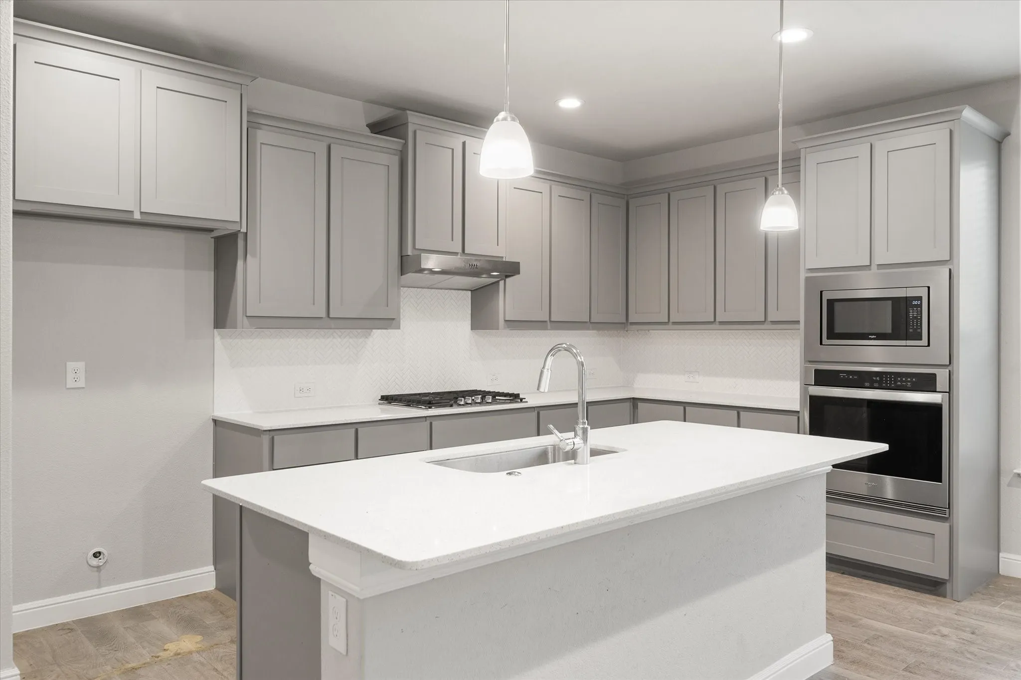 Open-concept kitchen featuring an oversized island with an integrated sink, shaker-style cabinetry, stainless steel appliances, a gas cooktop, and a mosaic tile backsplash