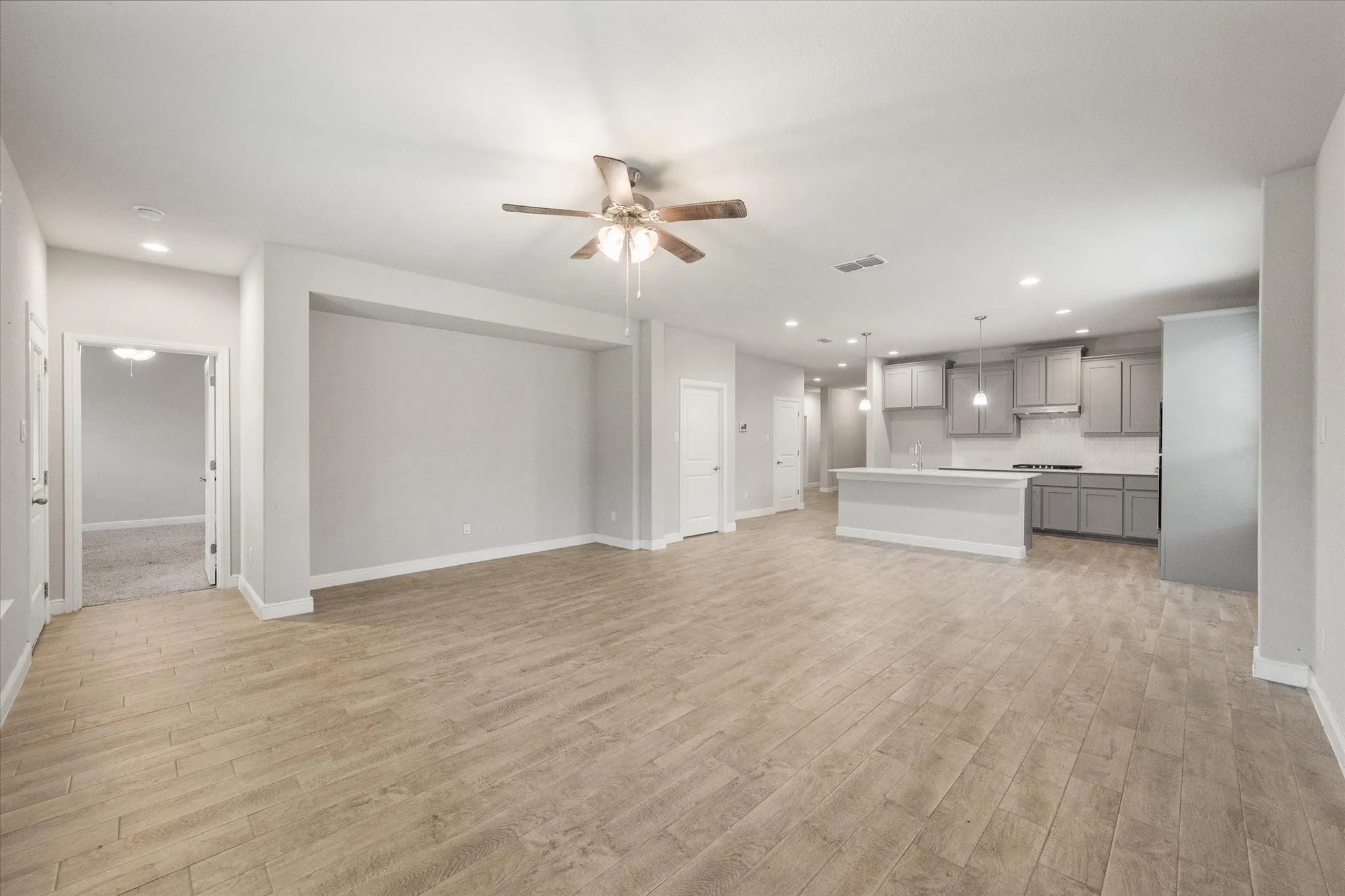 Open-concept living space featuring wood-look tile flooring, recessed lighting, and a ceiling fan.