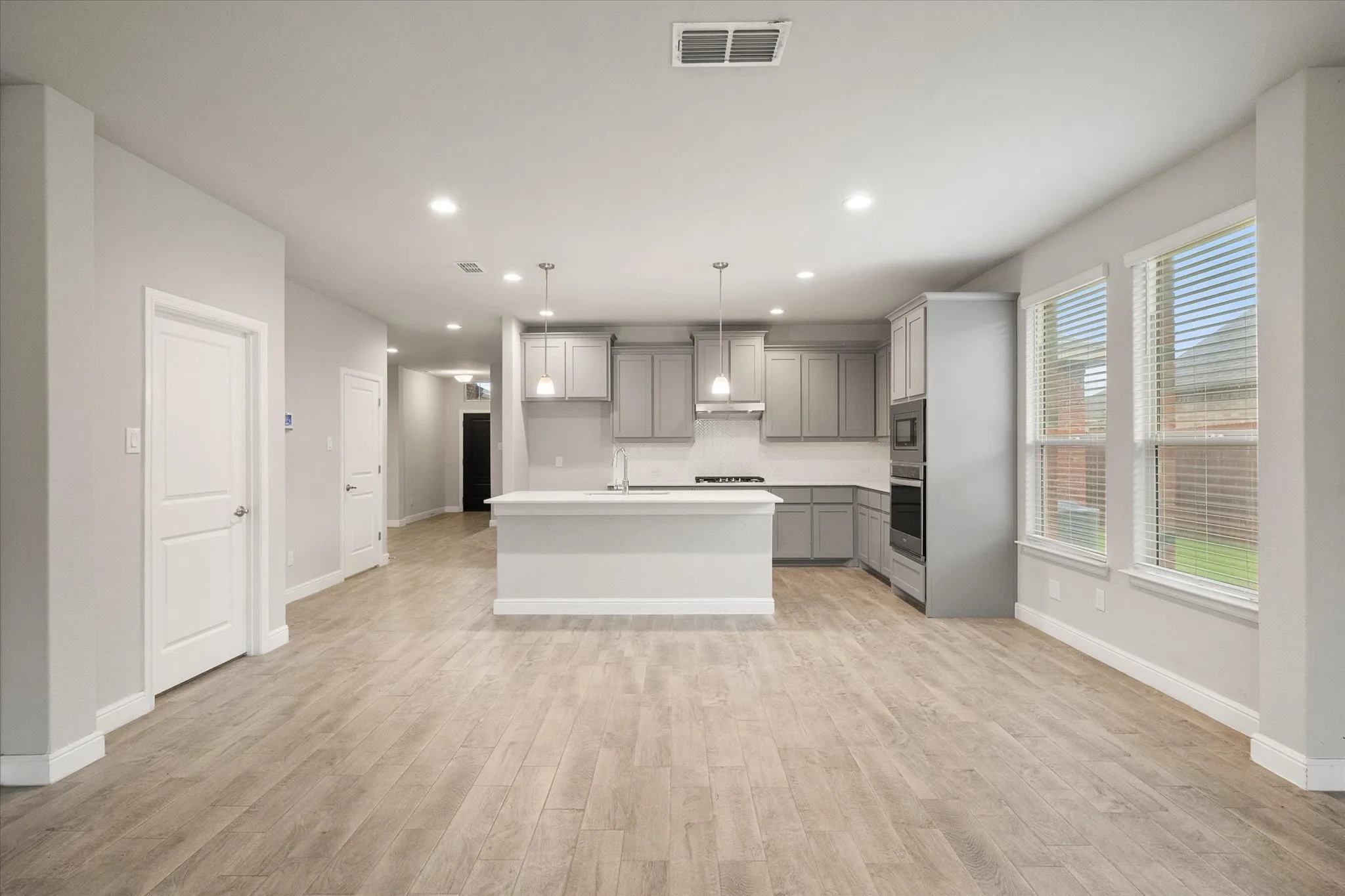 Open-concept layout featuring wood-look tile flooring, recessed lighting, and a kitchen island with pendant lights