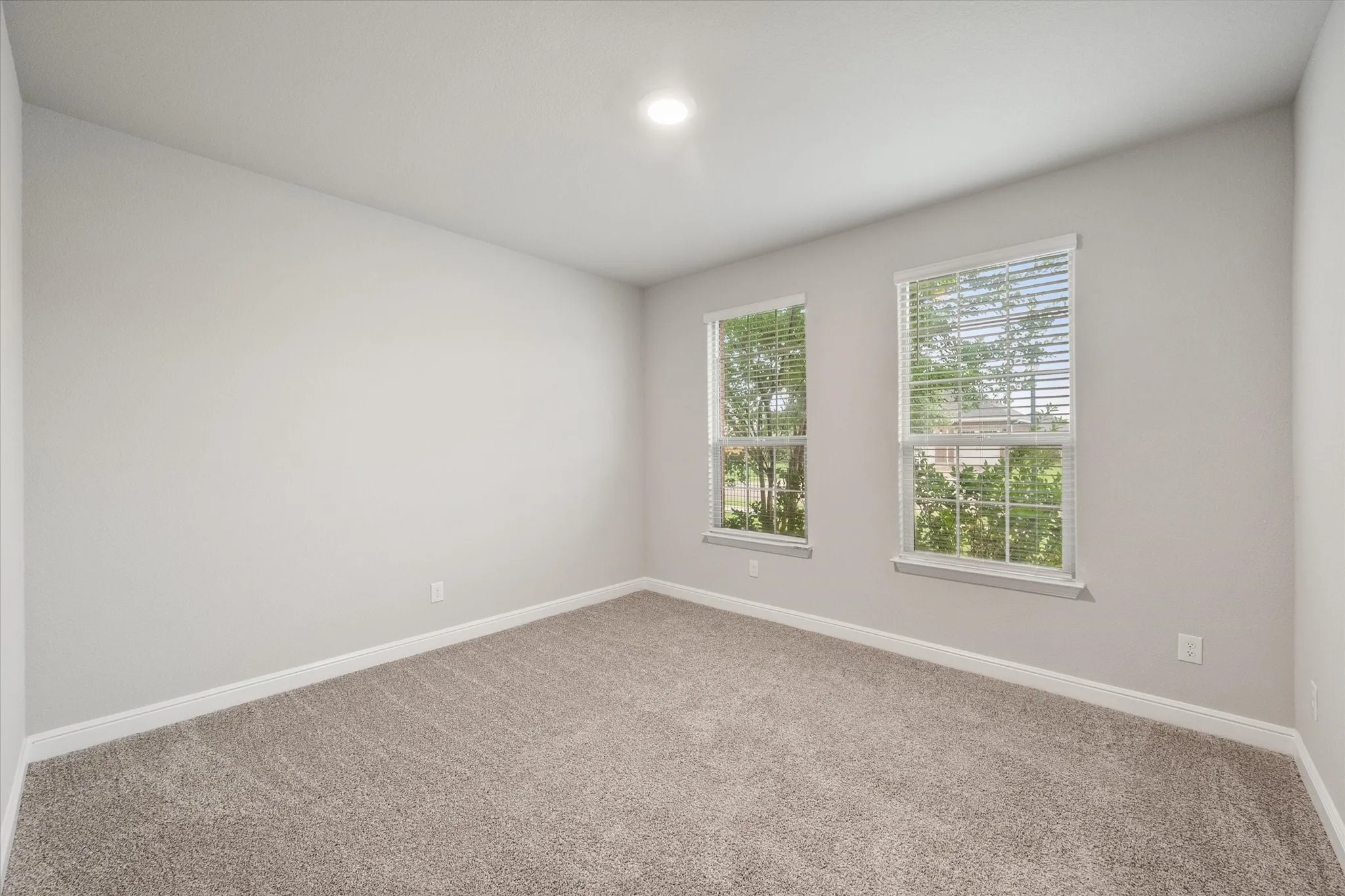 Bedroom 2 featuring two windows with white blinds, neutral wall paint, and plush carpet flooring