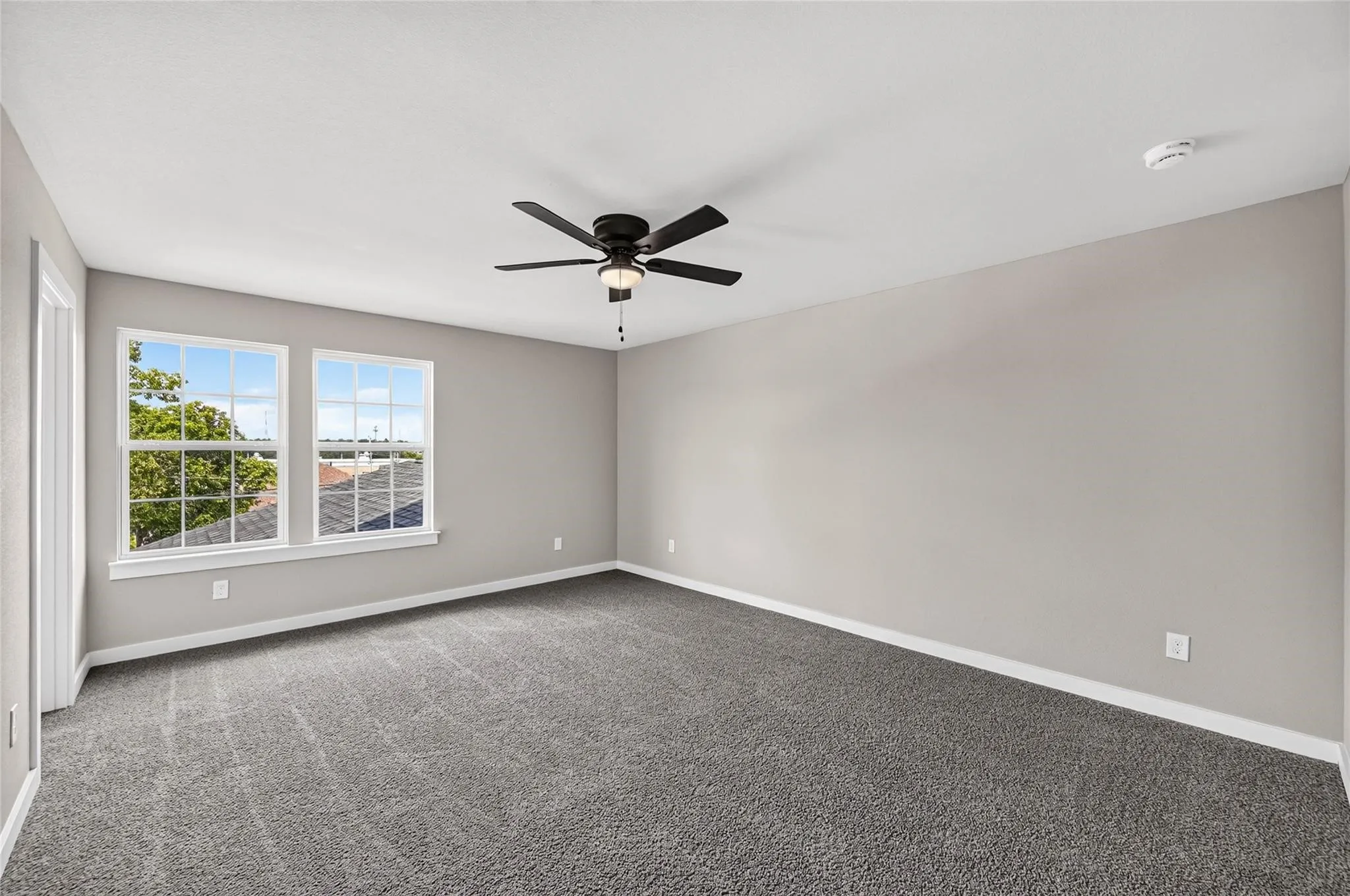 Spacious room with plush carpeting, neutral wall tones, and two windows
