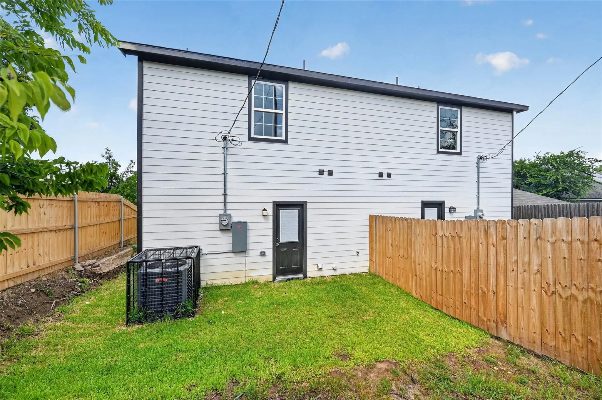 Two-story exterior with horizontal siding, multiple windows, a rear entry door, and a fenced yard