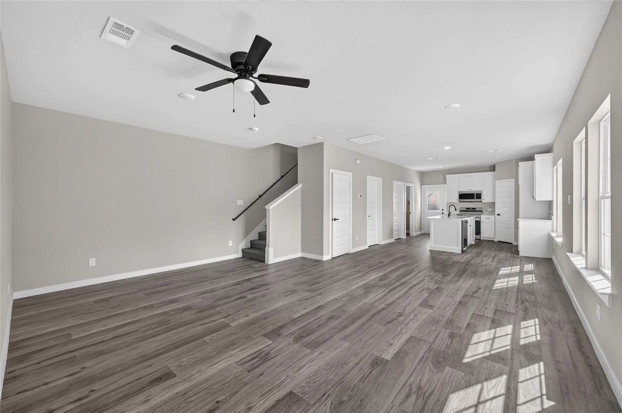 Open-concept living space featuring wood-finish flooring, recessed lighting, and a ceiling fan