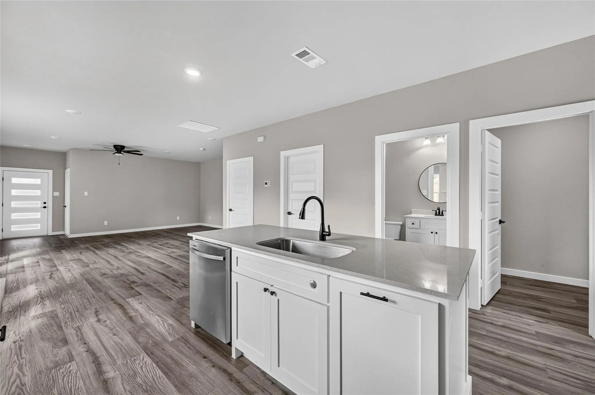 Kitchen island with a built-in sink, stainless steel dishwasher, and light-toned countertop
