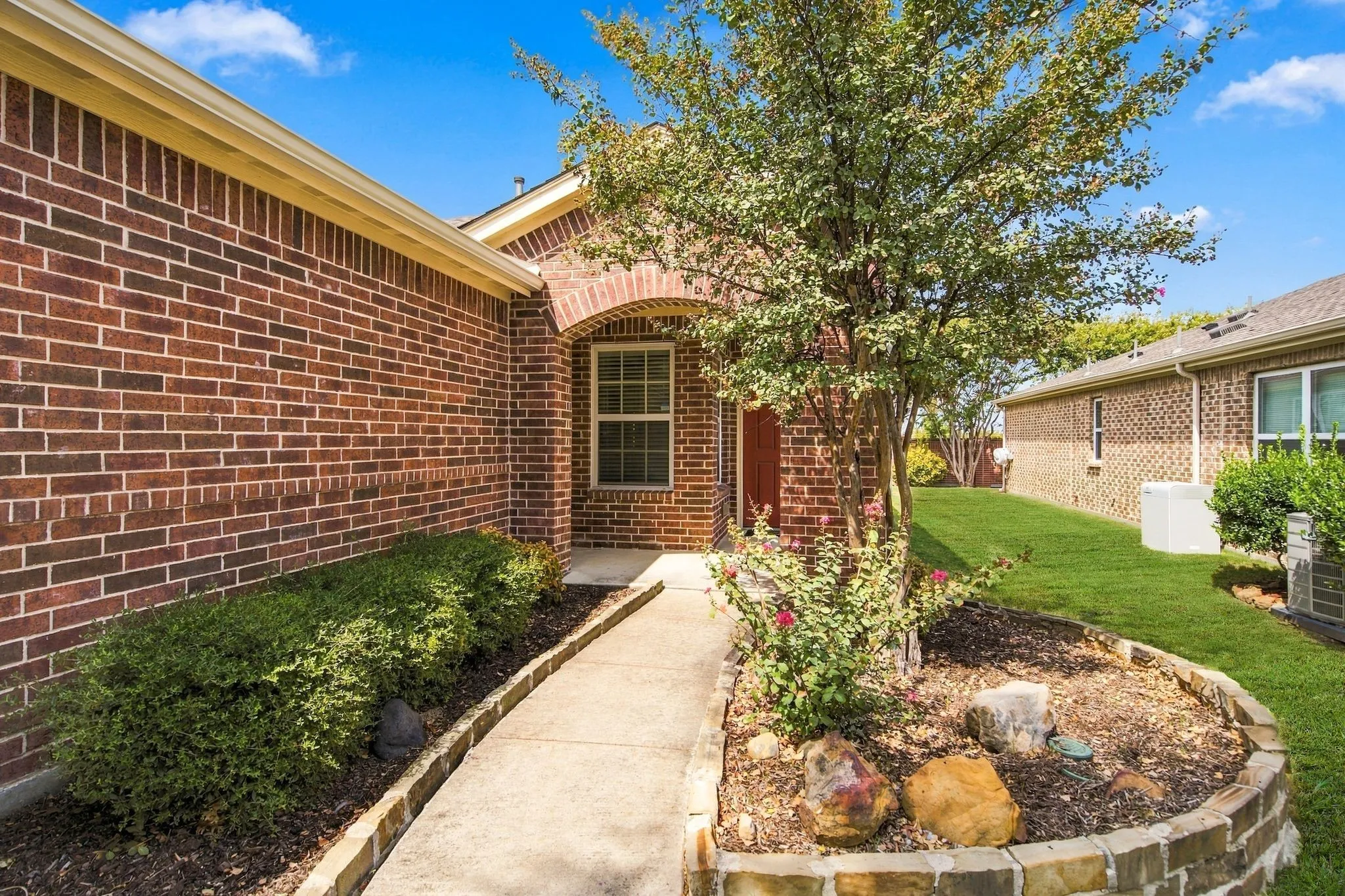 Attractive Arched Entryway And Stone-Edged Landscaping.