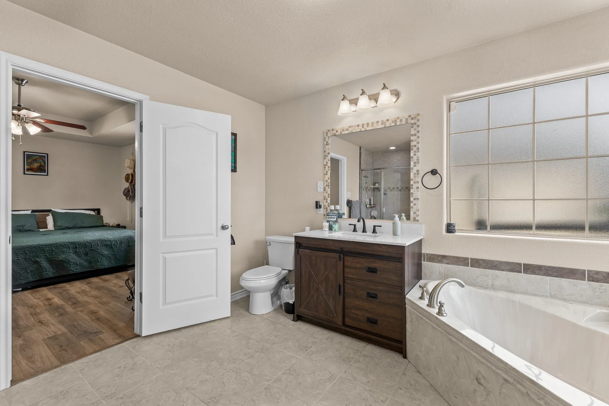 Bathroom featuring a built-in tub, single vanity with a white countertop, and a tiled mirror frame