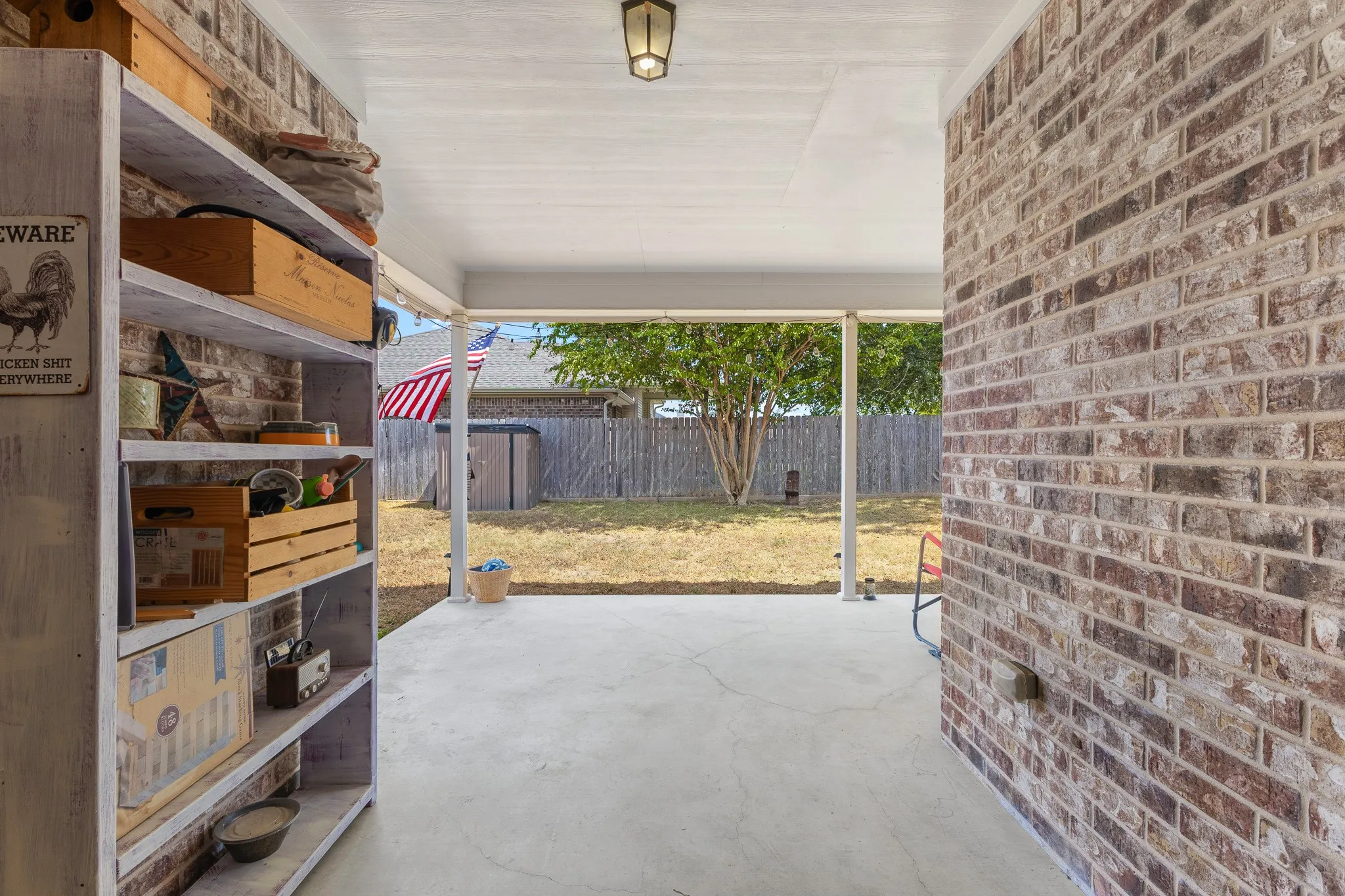 Covered patio with a concrete floor, brick exterior wall, and a textured white ceiling