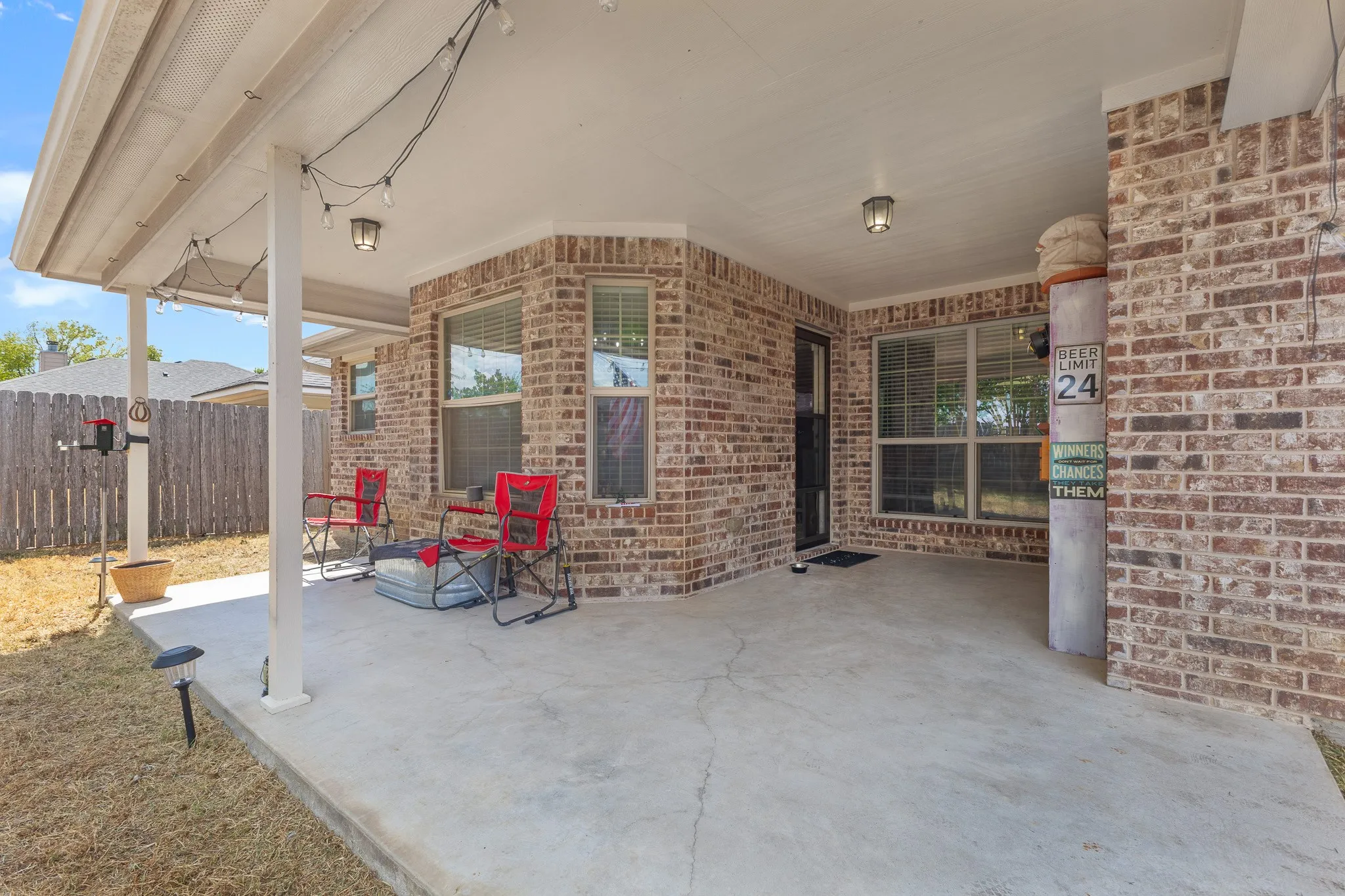 Covered patio with a concrete slab, brick exterior, and multiple windows