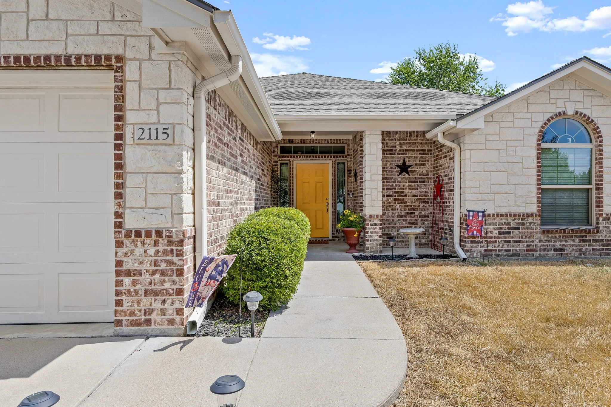 Brick and stone façade with arched window detail, covered entry, and attached garage
