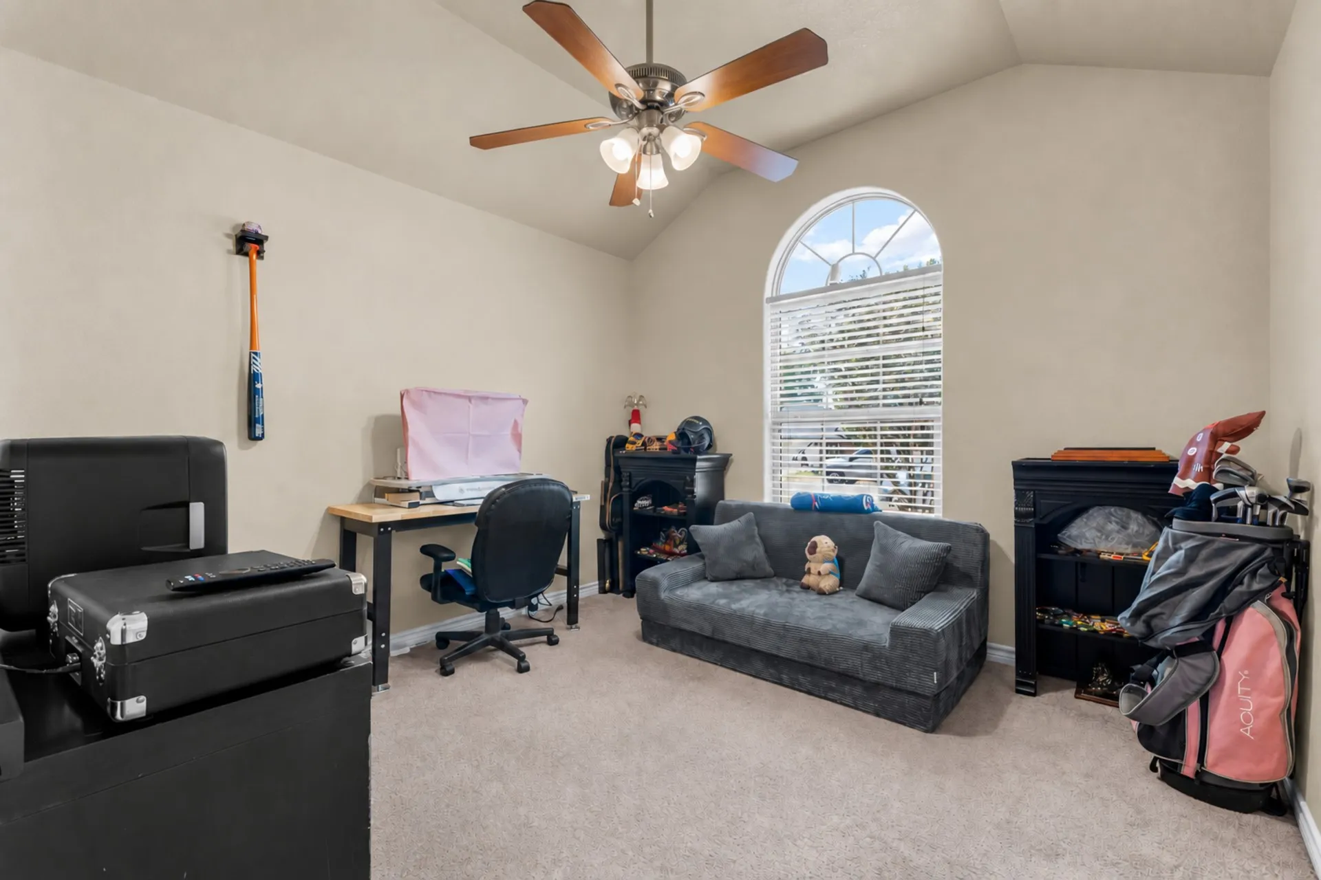 Vaulted ceiling with a ceiling fan, arched window with horizontal blinds, and carpeted flooring