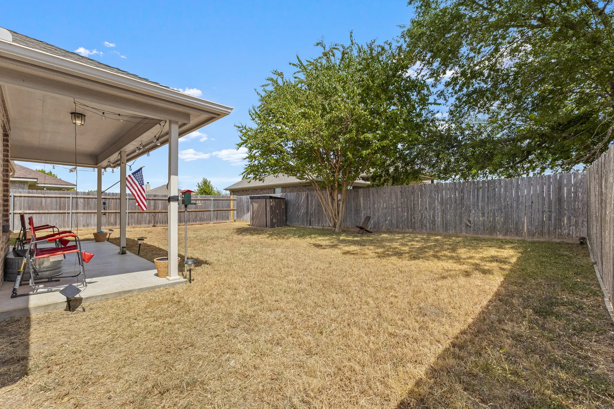 Covered patio with exterior lighting and a wood privacy fence