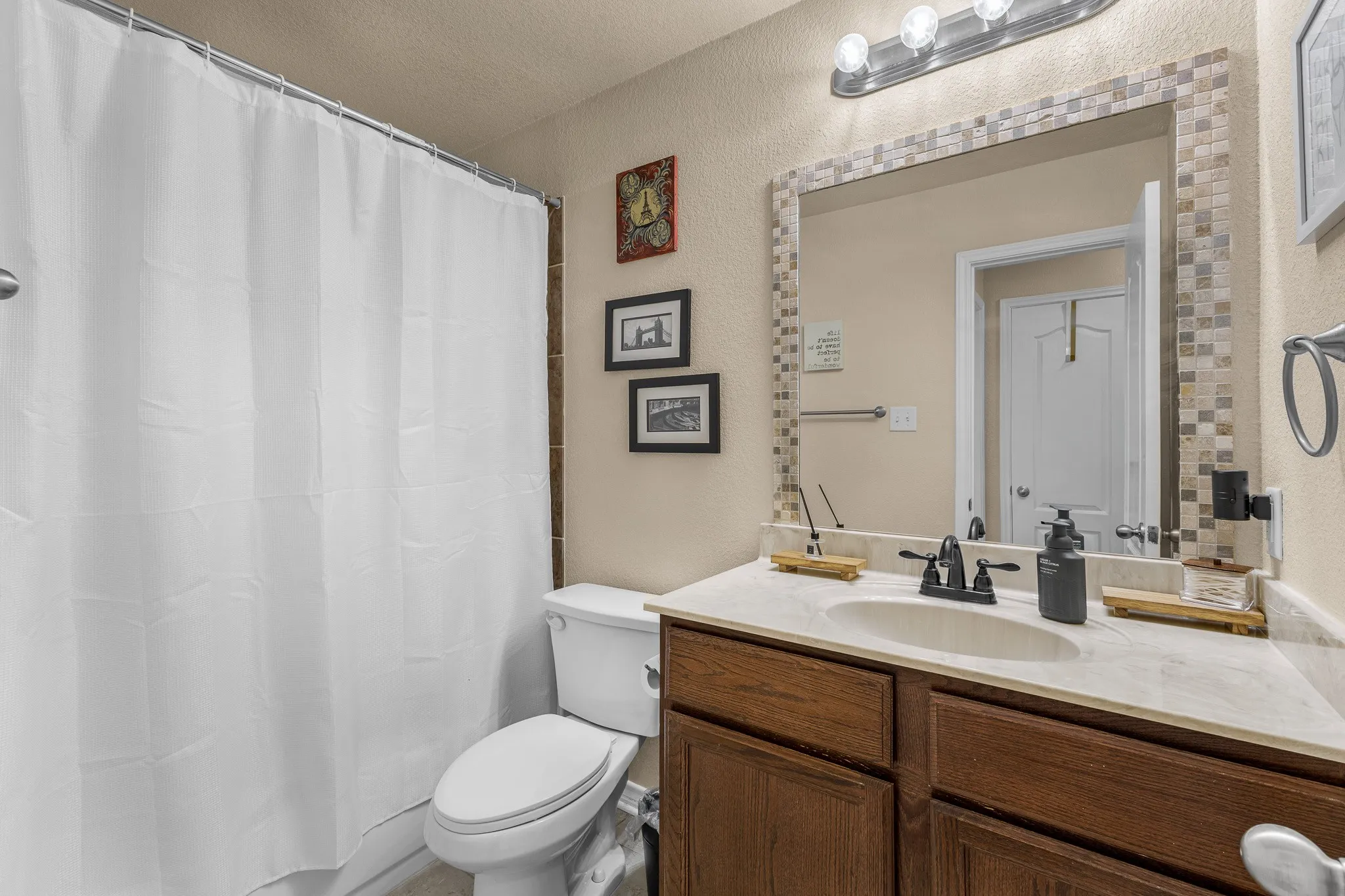 Bathroom featuring a wood-finish vanity with an integrated sink and light-colored countertop