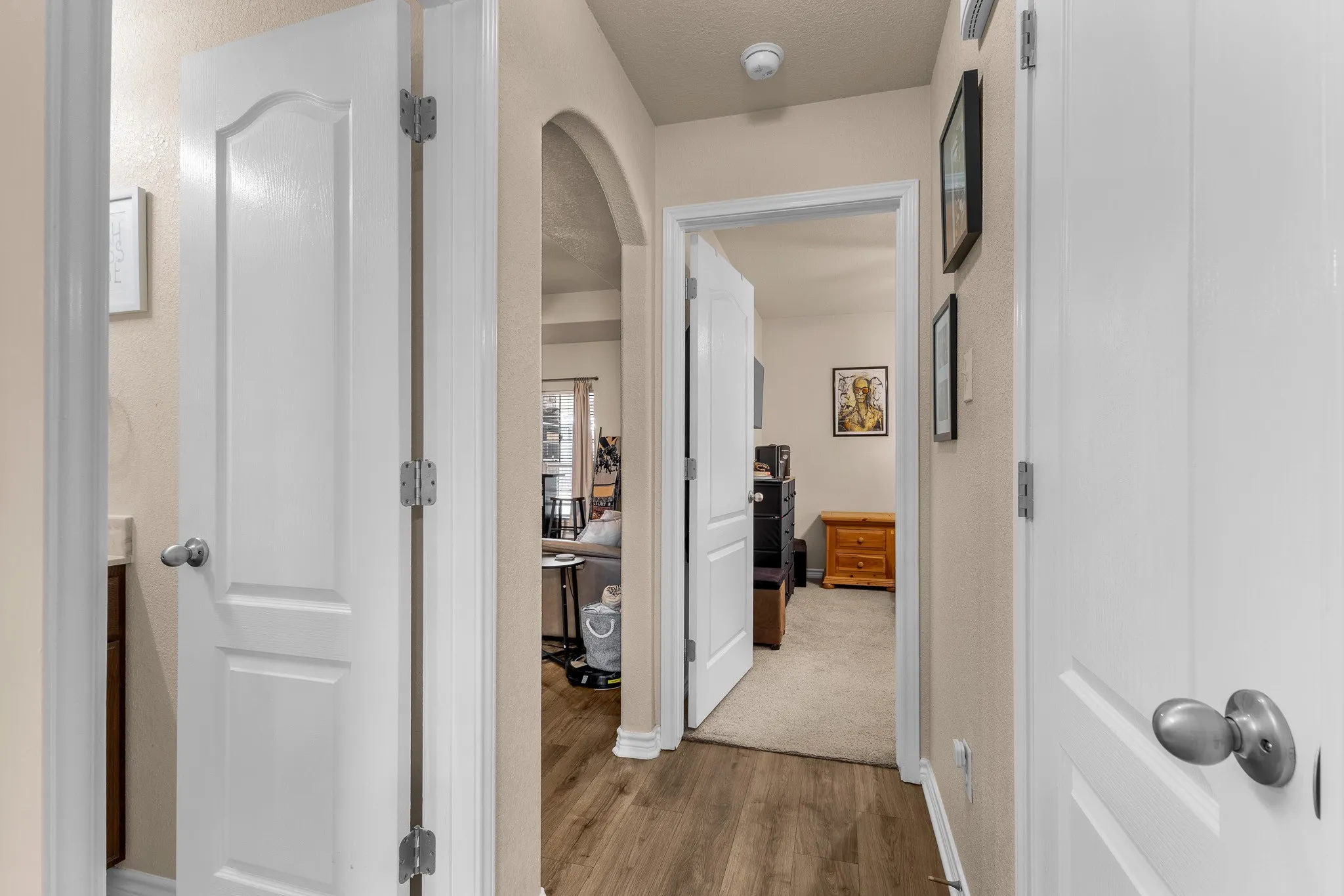 Wood-finish flooring, arched entryway, and paneled interior doors
