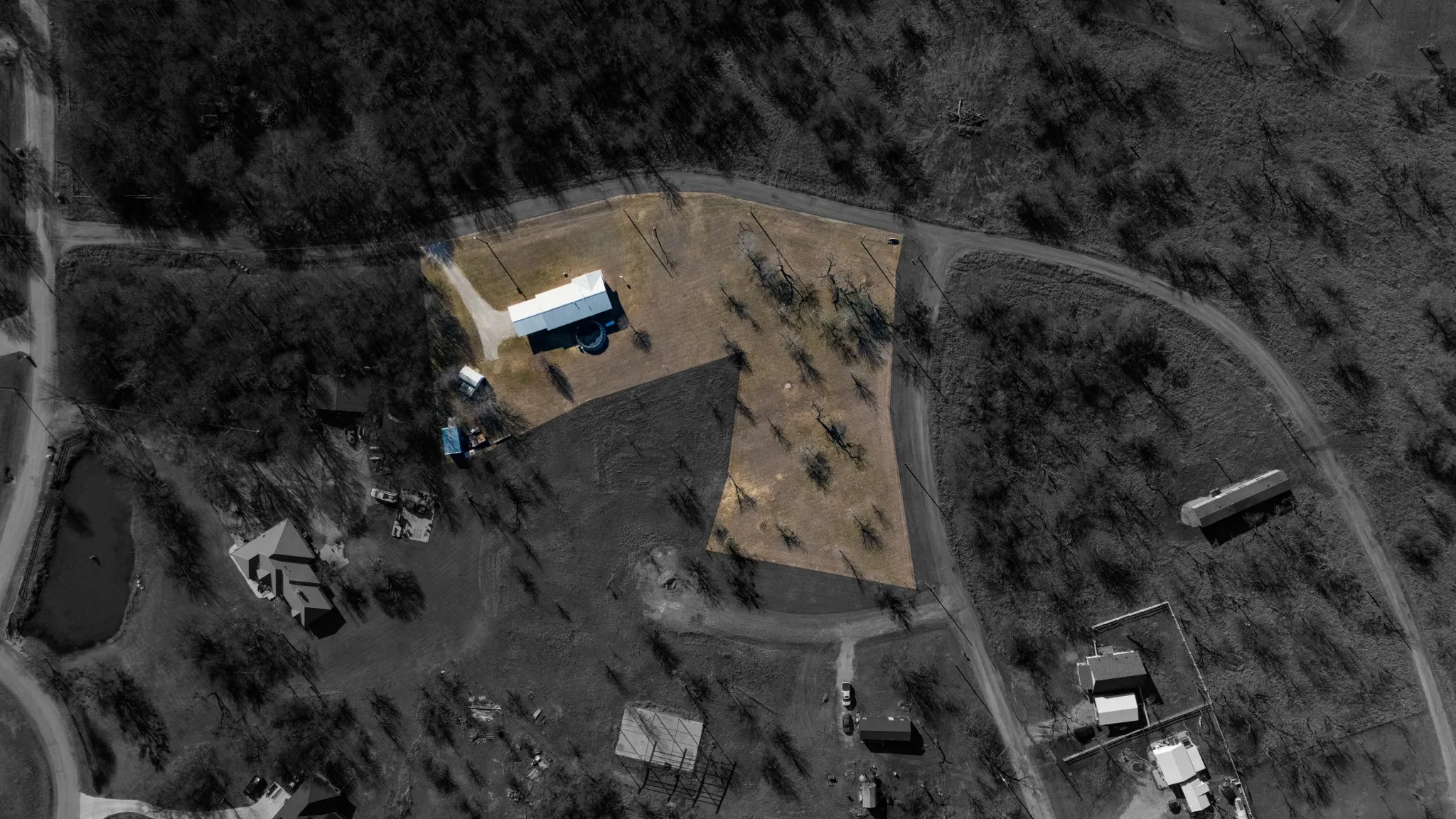 Expansive lot featuring a single-story structure, a detached outbuilding, and a paved driveway