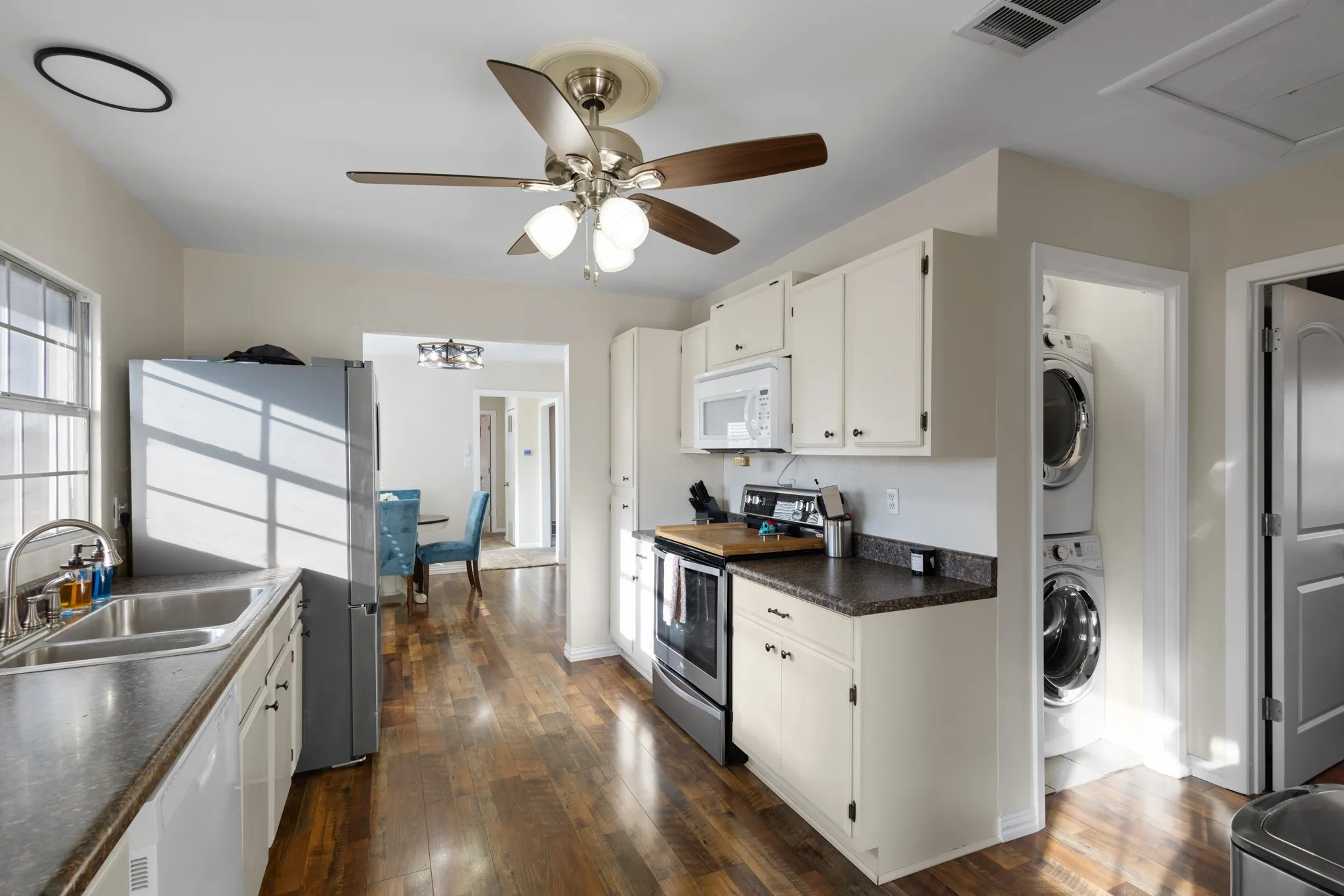 Kitchen featuring wood-finish flooring, white cabinetry, a double basin sink, and built-in appliances