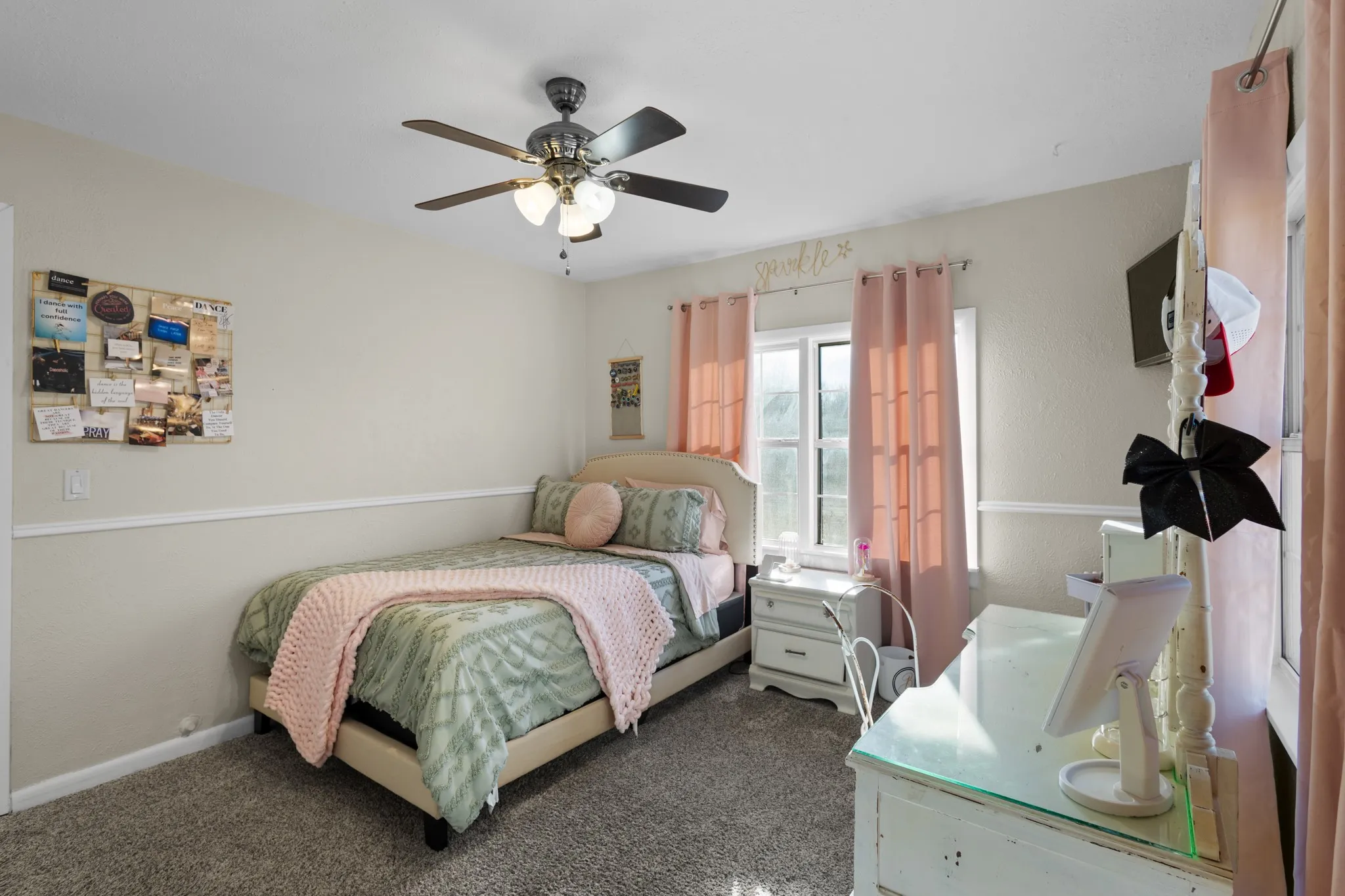 Carpeted room with a ceiling fan light fixture, a window with trim, and a chair rail molding