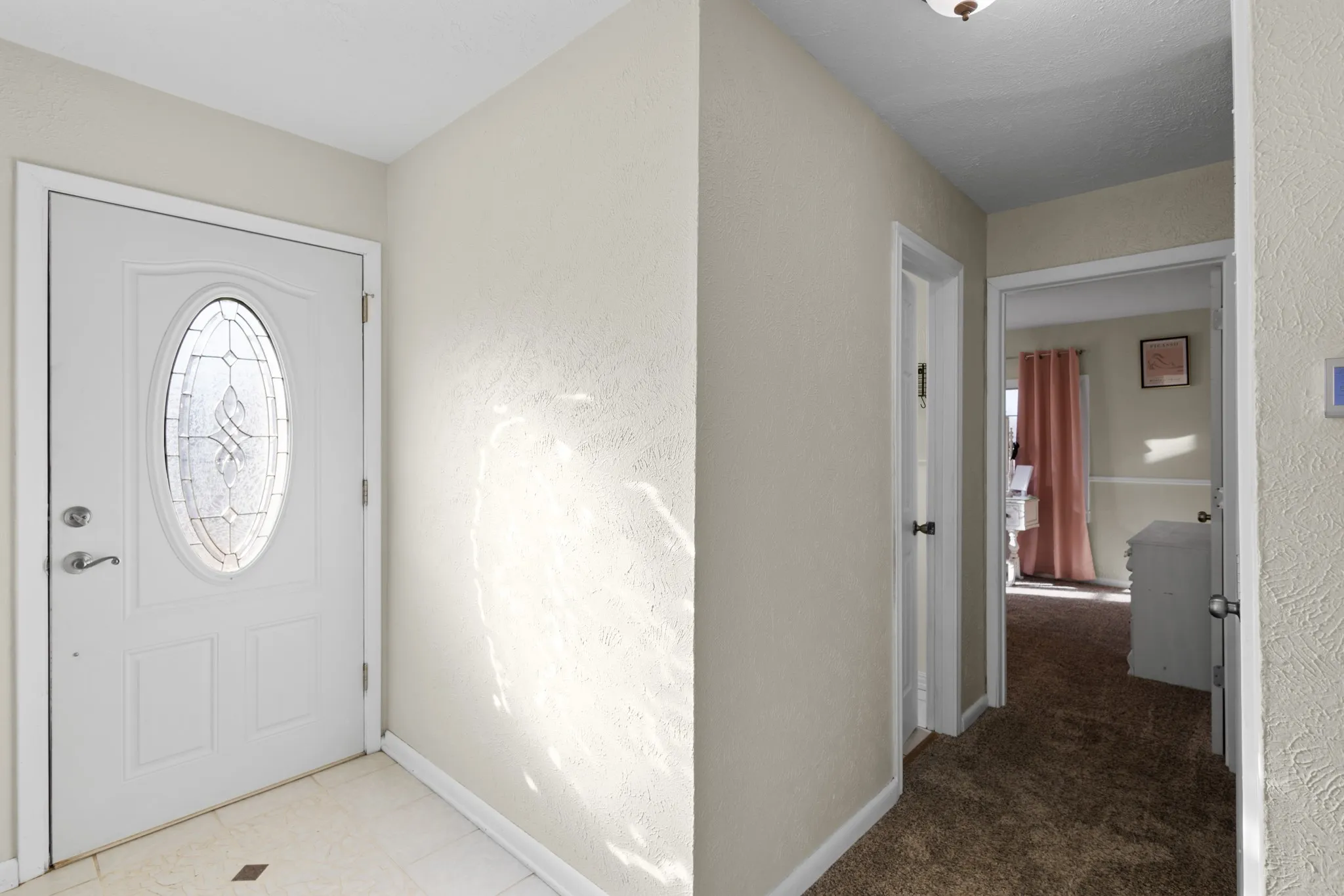 Entryway featuring a decorative oval glass front door, neutral wall tones, and tiled flooring