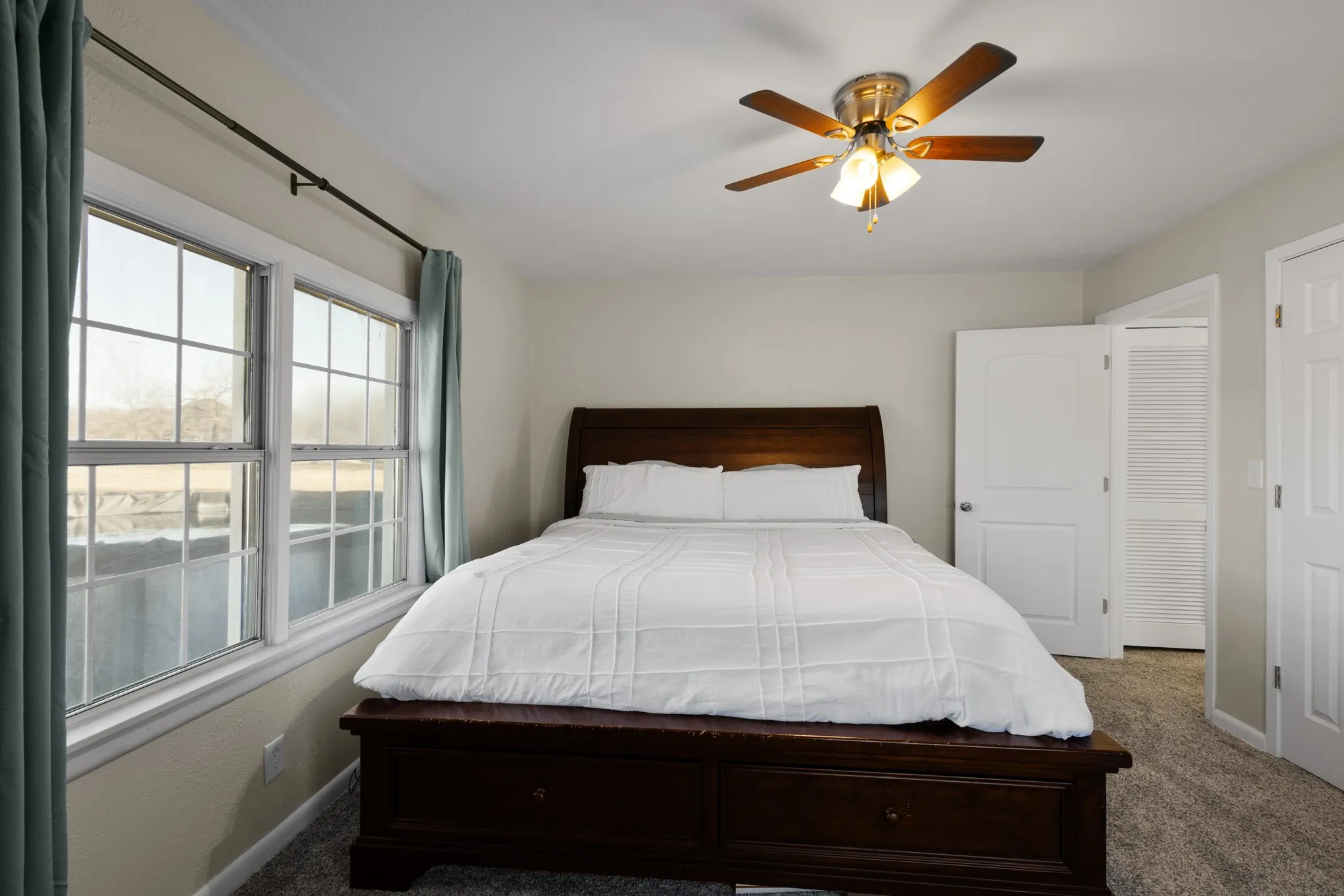 Neutral wall tones with carpet flooring, a multi-pane window, and a ceiling fan with integrated lighting