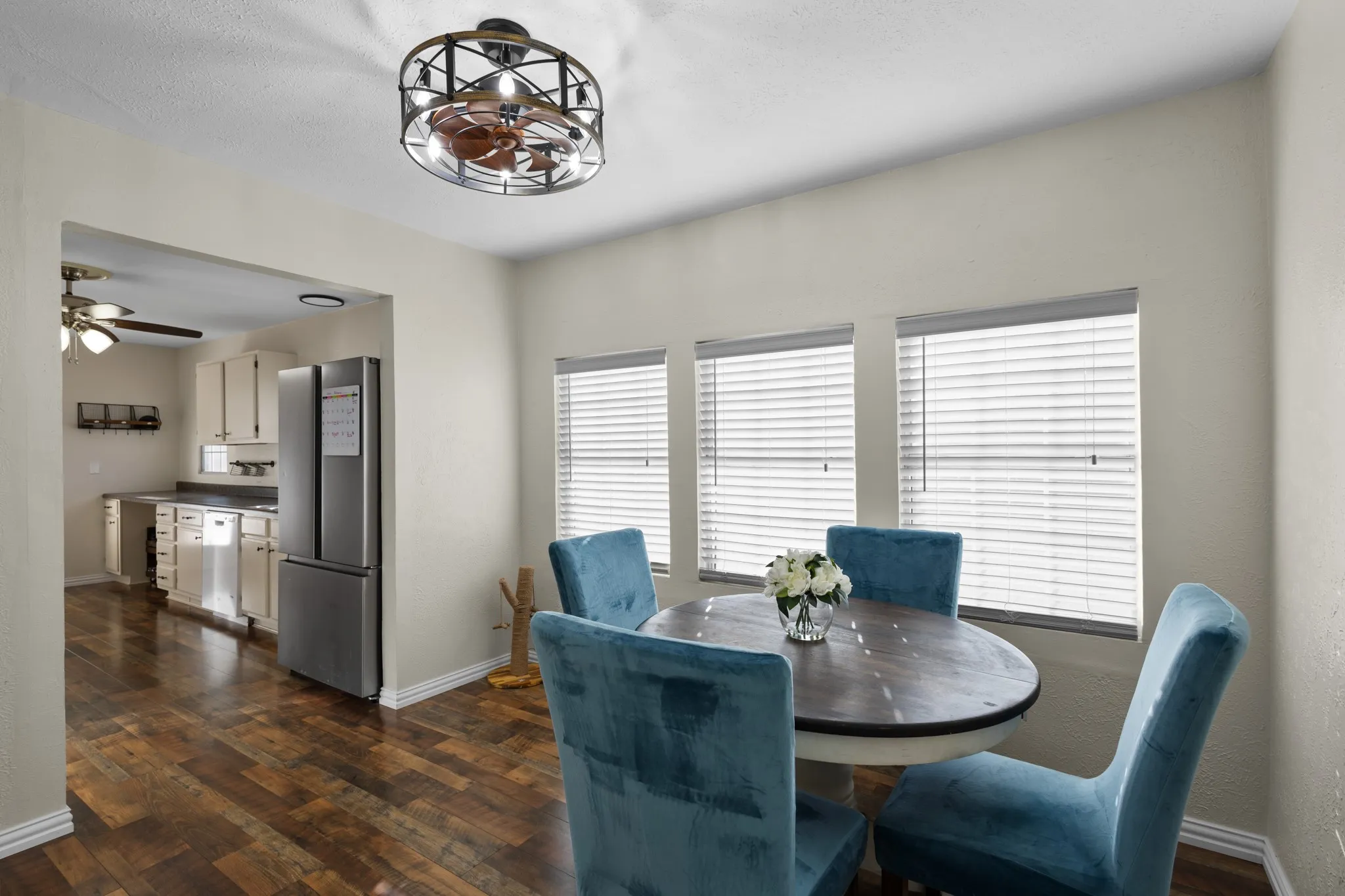Wood-finish flooring throughout, multiple windows with blinds, and a built-in ceiling fan with integrated lighting