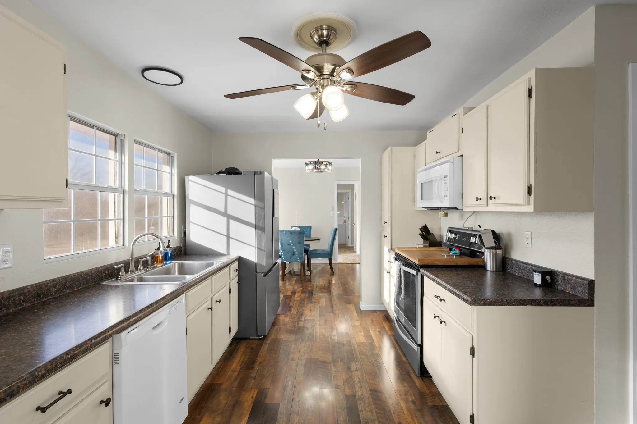 Kitchen featuring wood-finish flooring, ample cabinetry, dual basin sink, stainless steel refrigerator, and built-in microwave