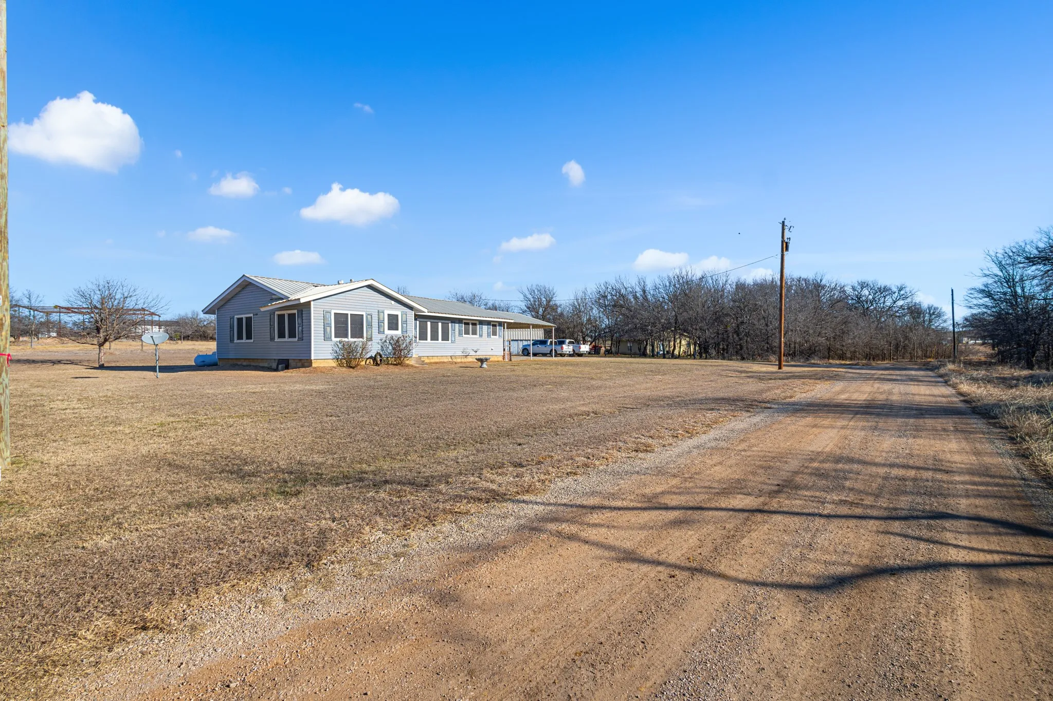 Ranch-style residence featuring a light gray exterior, multiple windows, and a metal roof