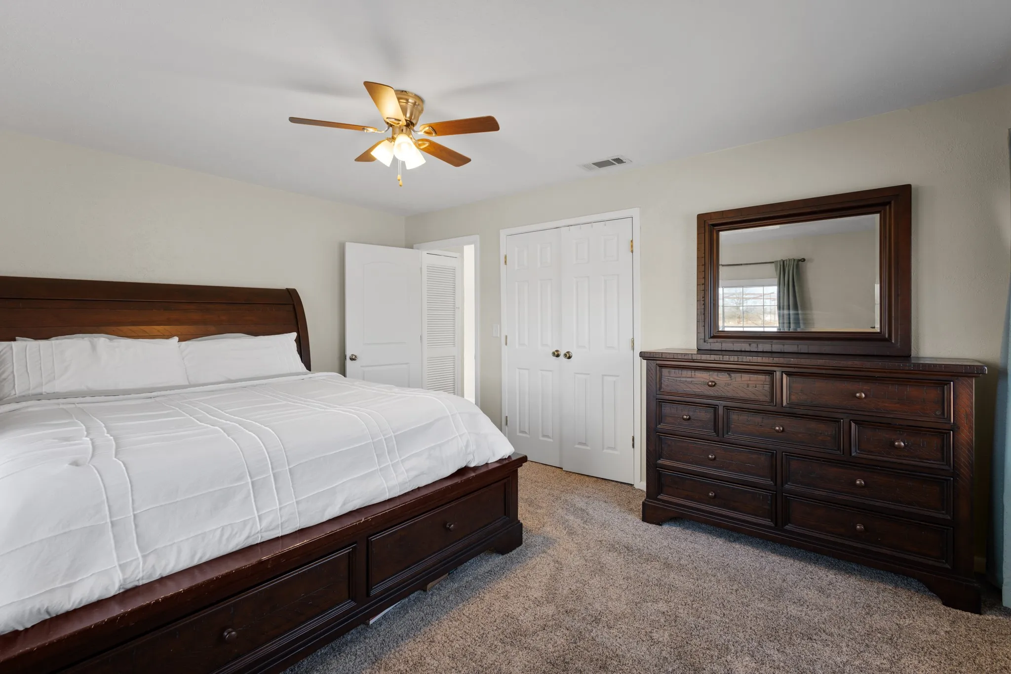 Plush carpet flooring, ceiling fan with integrated lighting, and multiple white panel doors