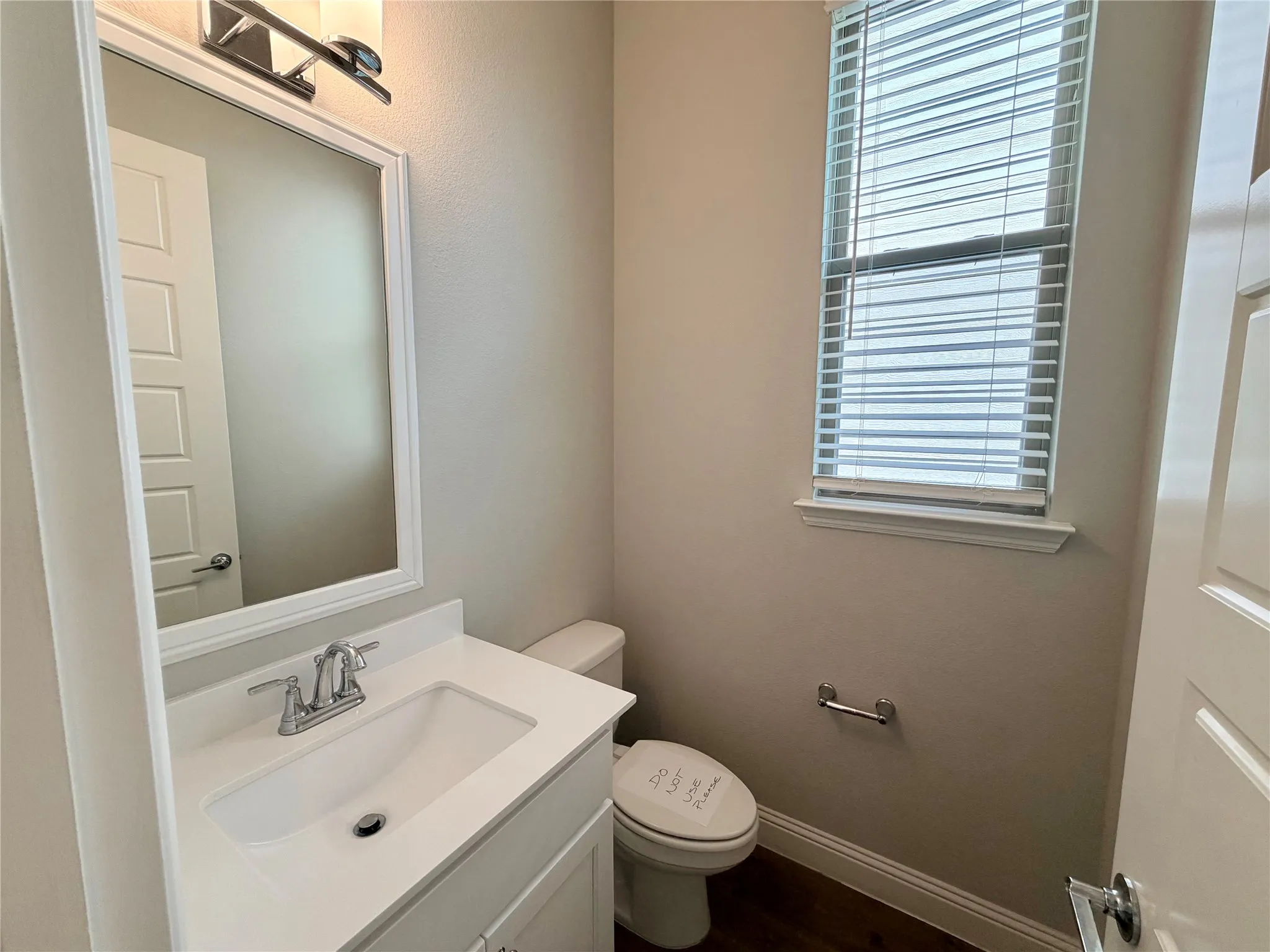 Vanity with an integrated sink, polished chrome faucet, framed mirror, and a window with blinds